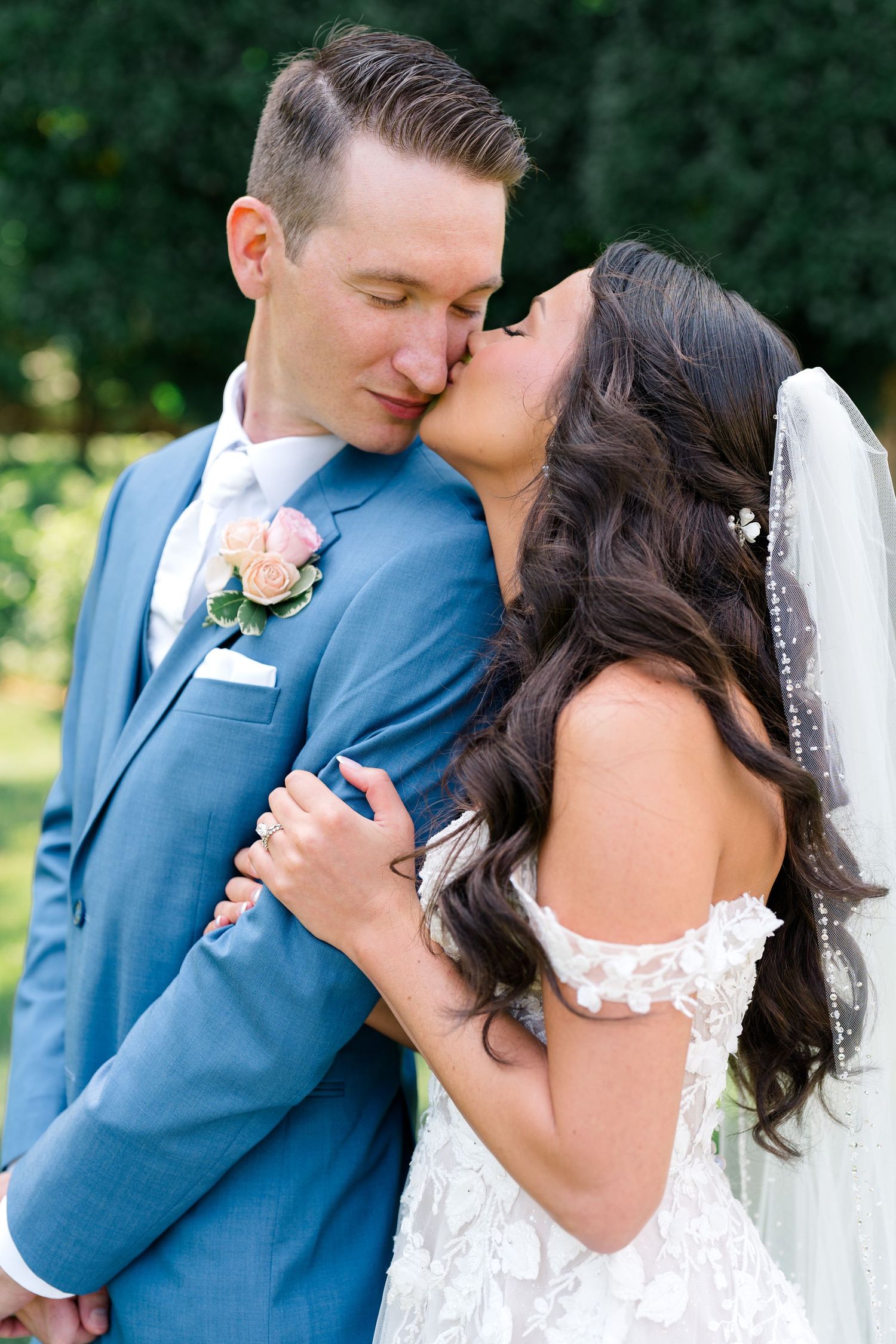 Wedding couple sharing intimate moment outdoors in blue suit and white dress.