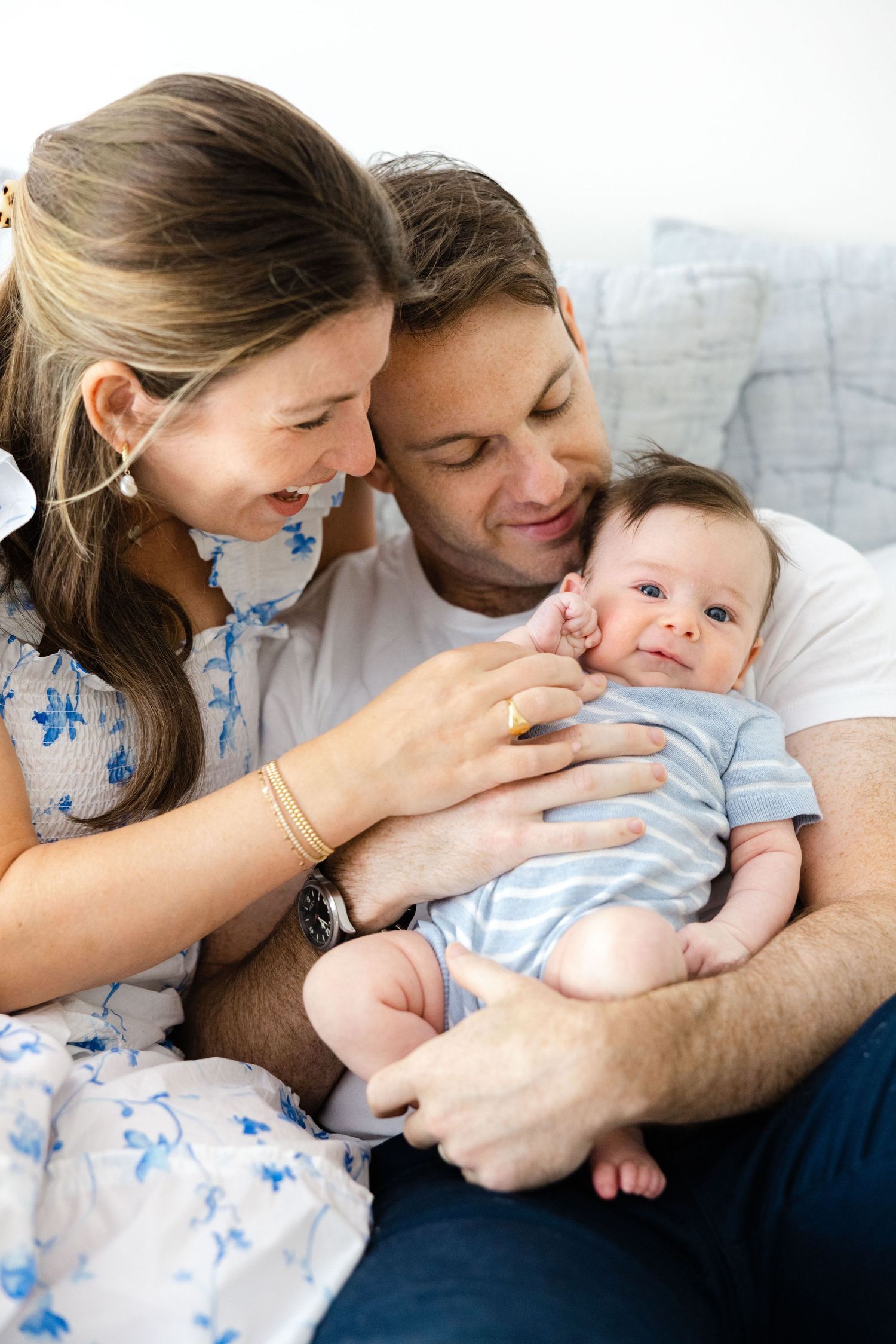 Parents sharing tender moments with their baby in a series of loving poses on white bedding.