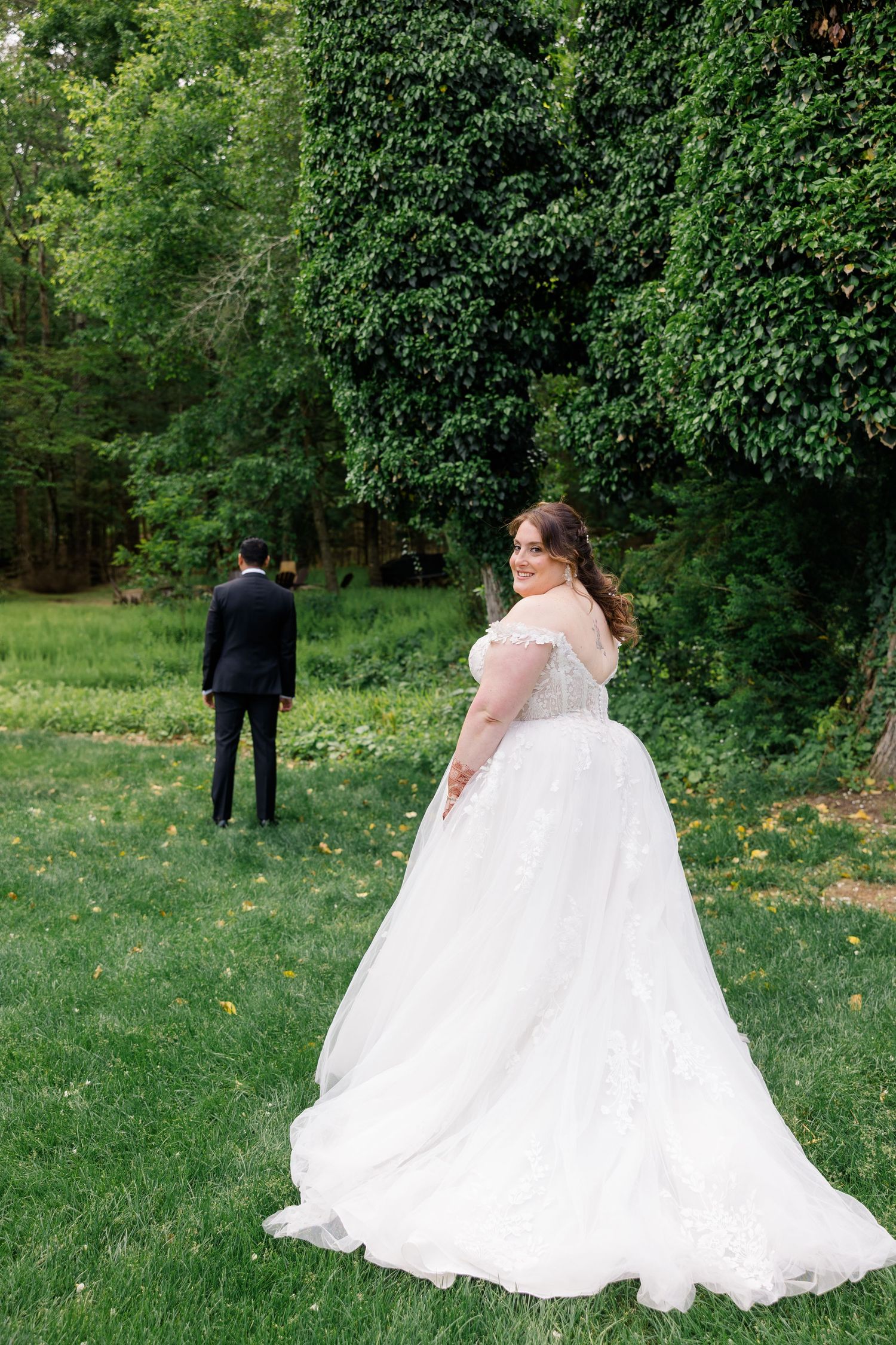A flowing white wedding dress on a grassy lawn with trees in the background.
