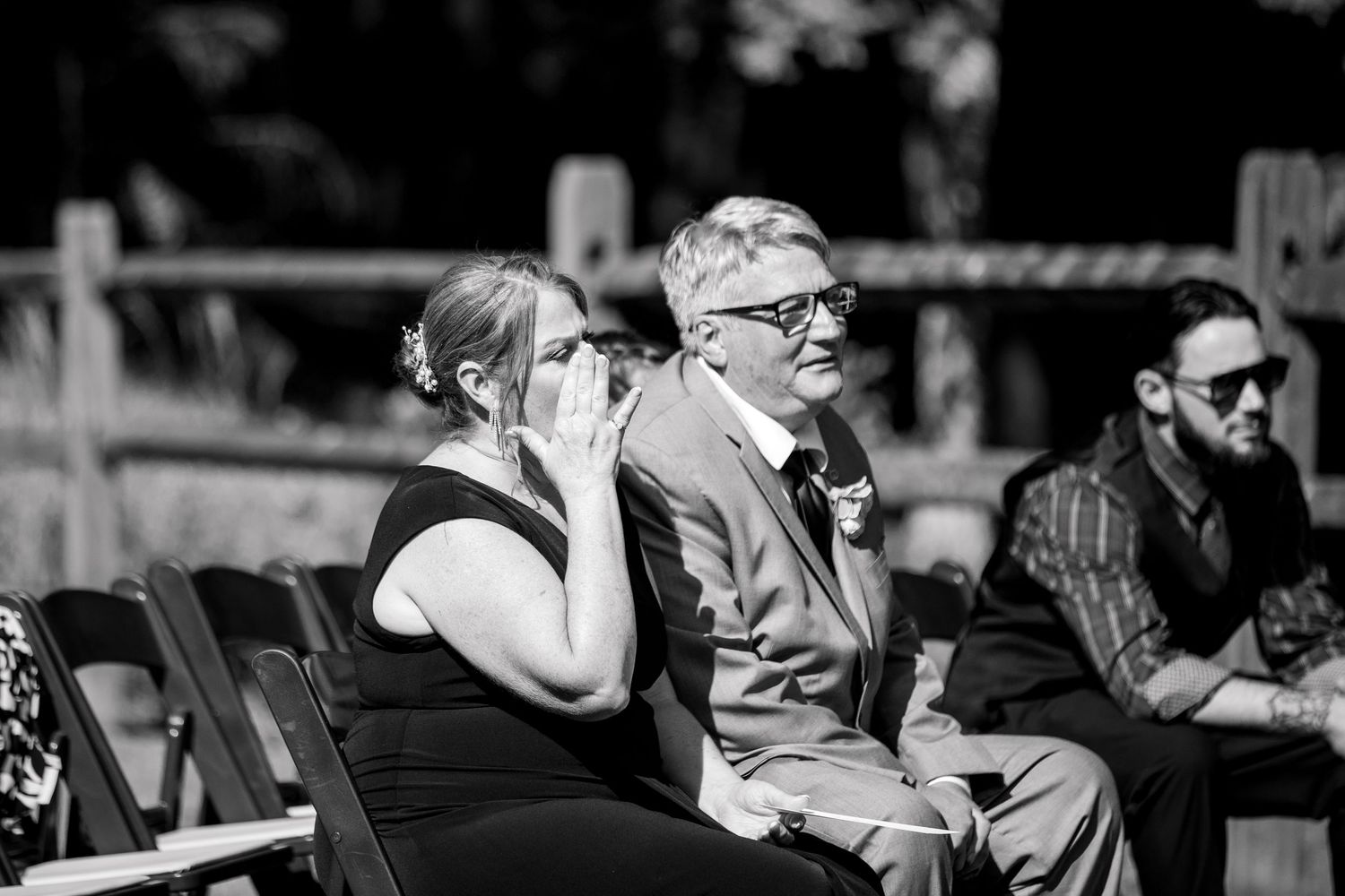 Black and white photo of wedding guests seated during an outdoor ceremony.