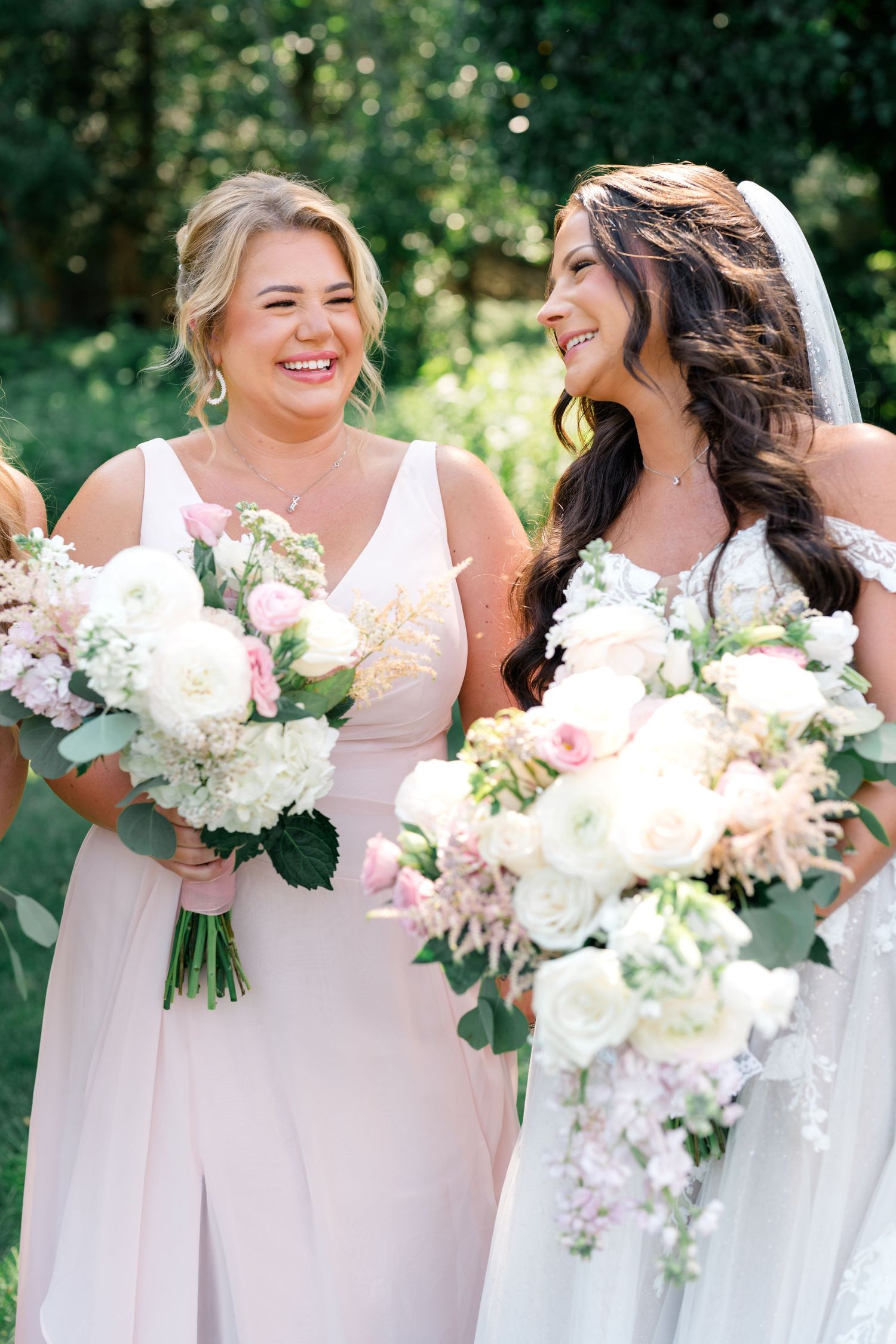 Bridesmaids in blush pink dresses holding white and pink floral bouquets.