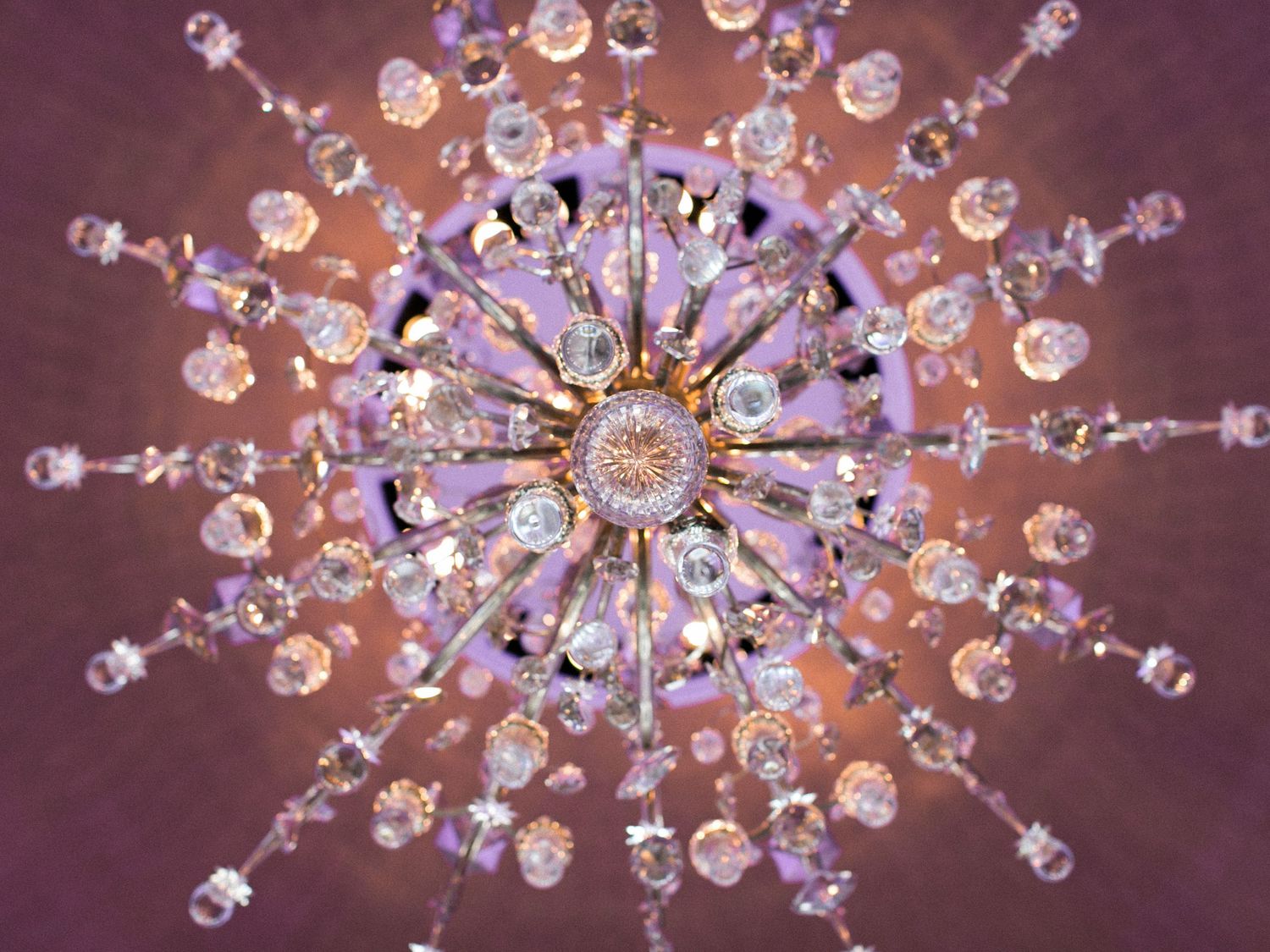 Close-up view of an elegant crystal chandelier with ornate glass details radiating in a starburst pattern.
