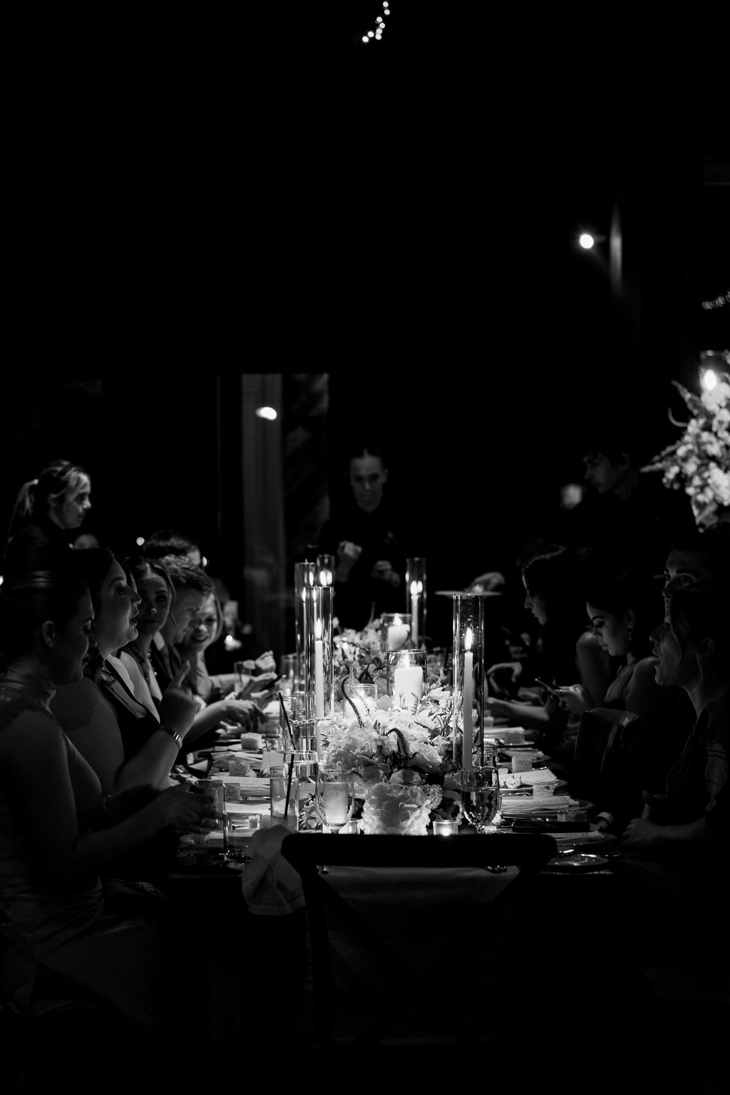 Candlelit wedding reception dinner table captured in dramatic black and white photography.