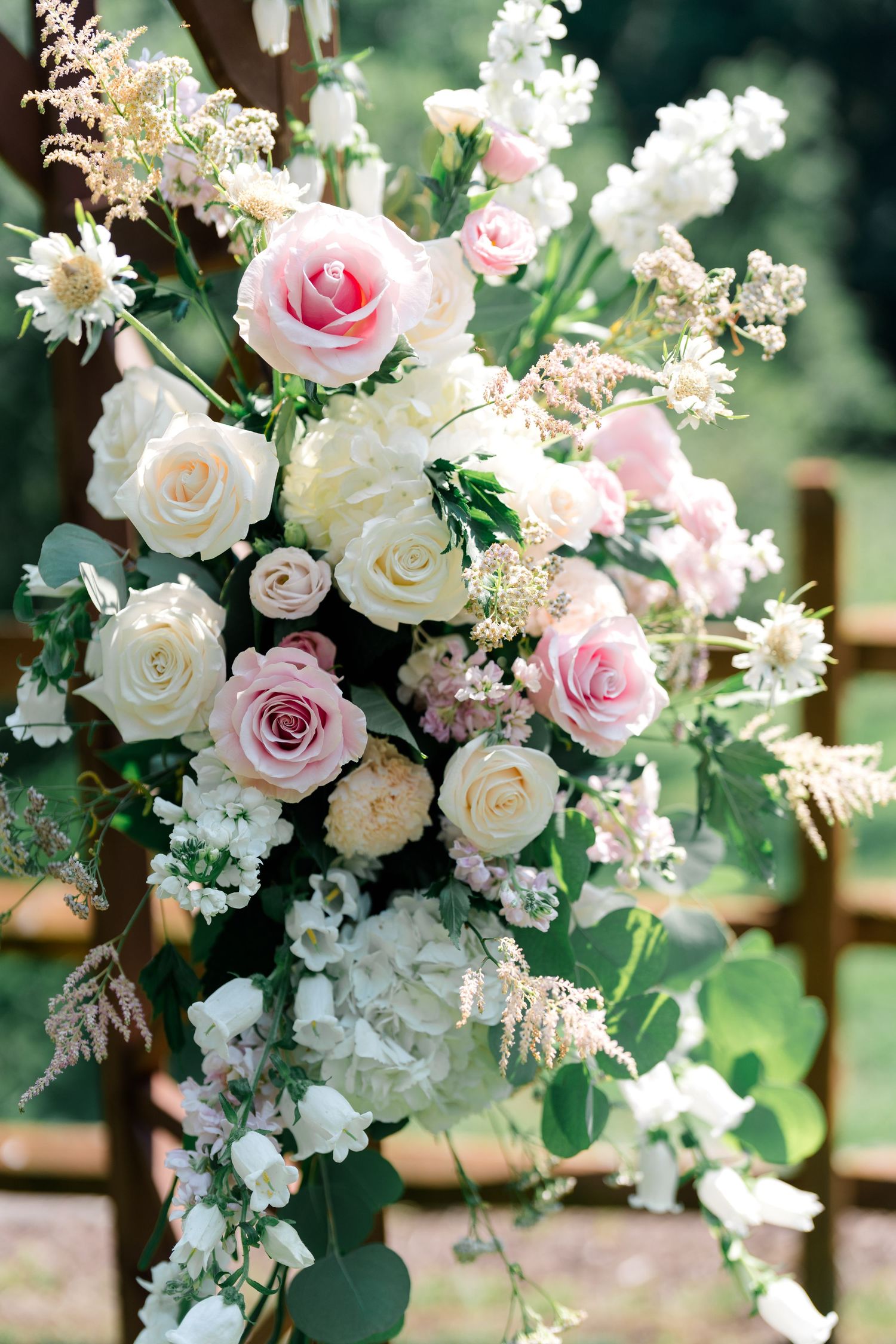 Elegant floral arrangement of pink and white roses with delicate greenery for wedding decor.