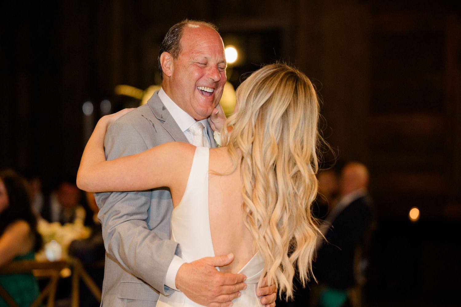 Romantic dance moment captured during wedding reception in warm lighting.