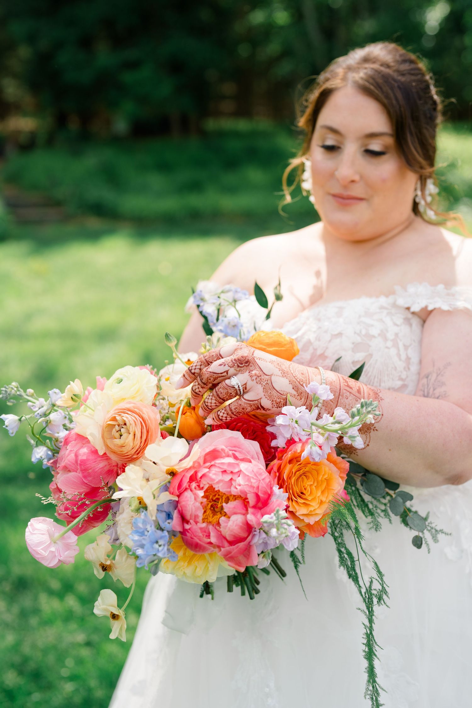 Vibrant coral and peach wedding bouquet with roses and mixed flowers.