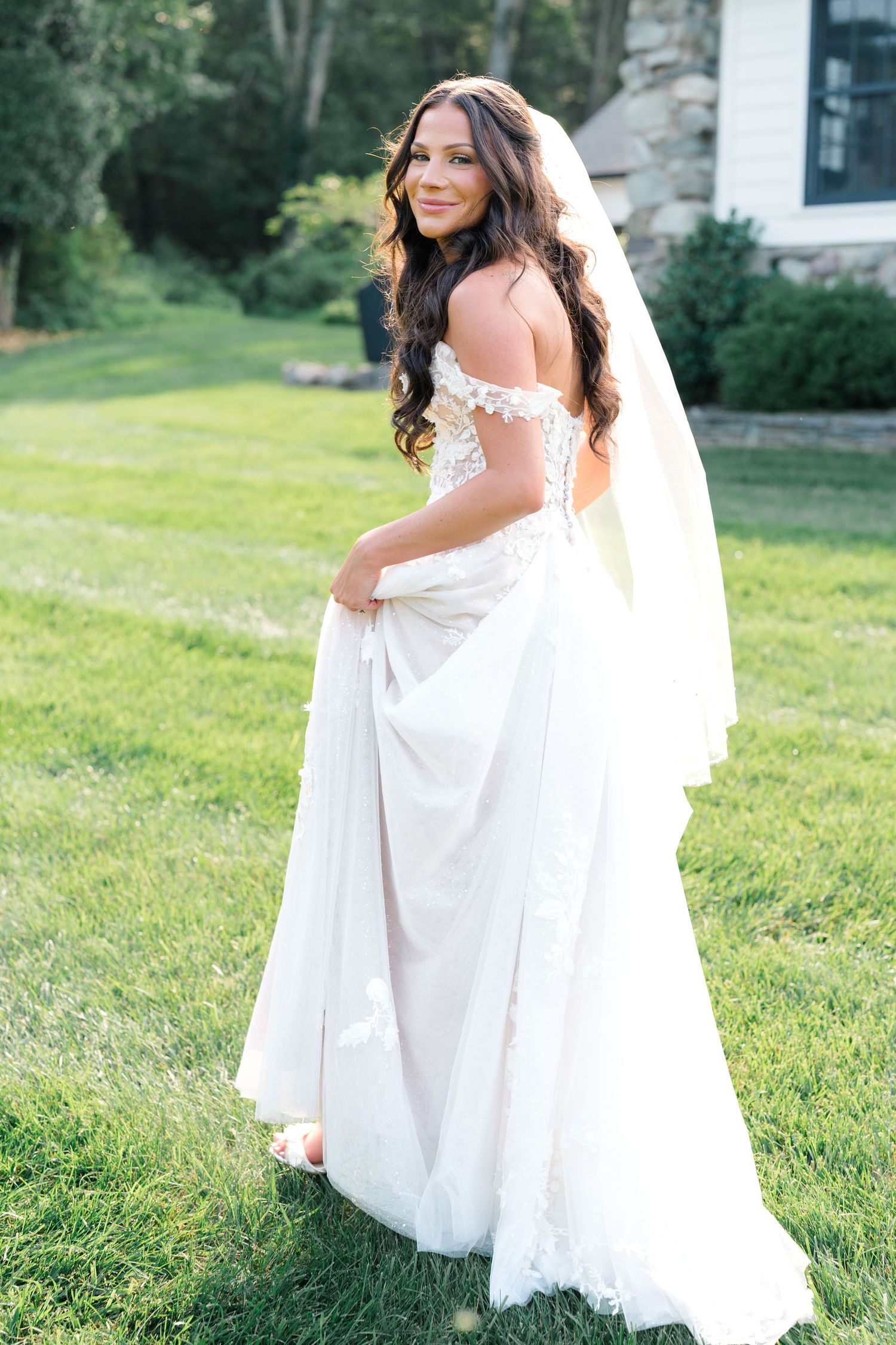 White wedding dress details on a grassy lawn showing elegant lace and flowing fabric.