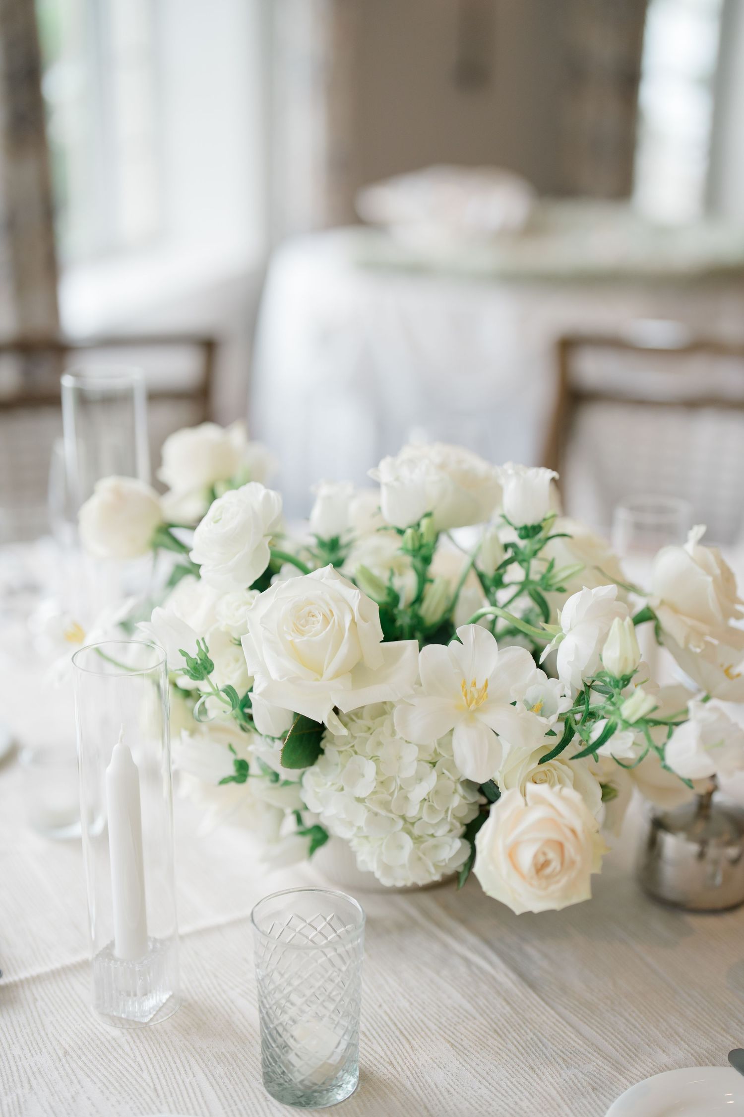 White roses and carnations arranged in cut crystal vases create an elegant tablescape centerpiece at a formal event.