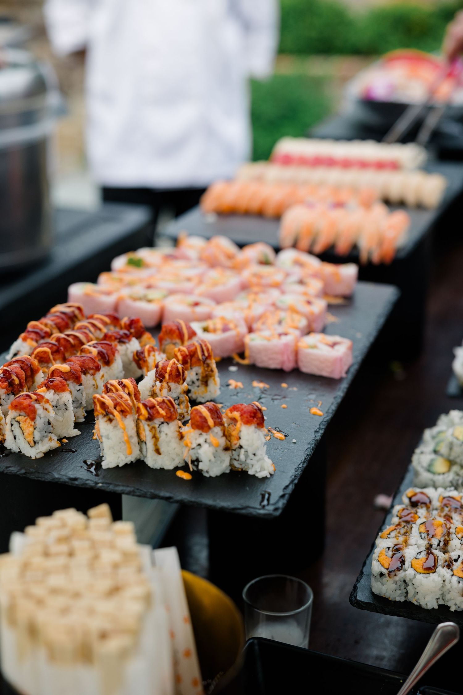 Fresh sushi rolls beautifully arranged on black serving platters at an elegant catering display.