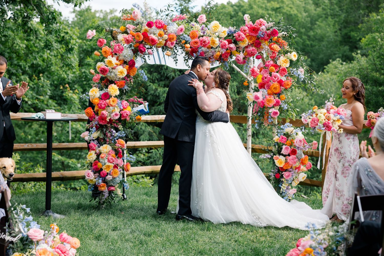 Wedding ceremony gathering with vibrant floral decorations in an outdoor garden setting.