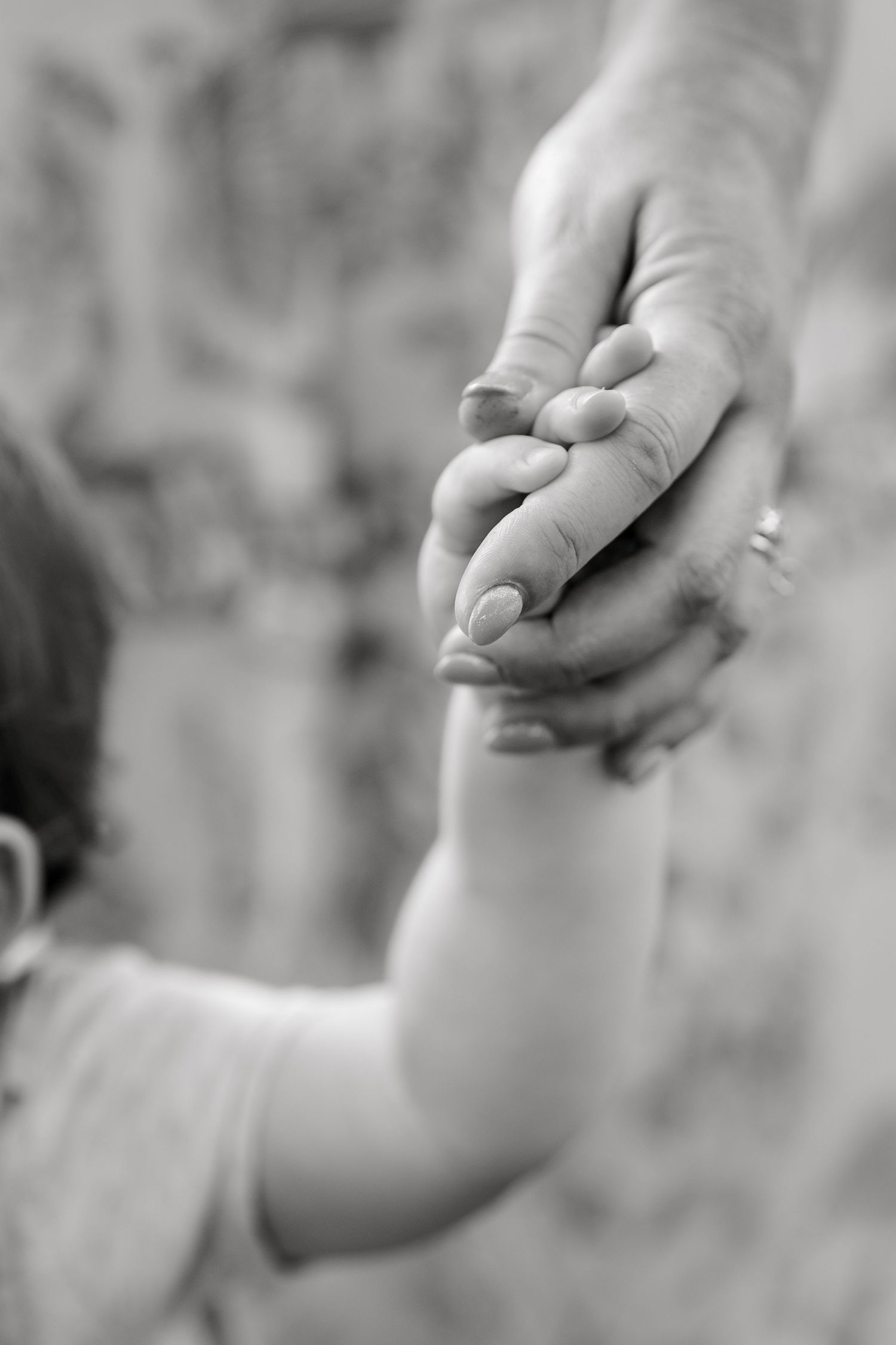 Black and white photo of a child holding an adult's hand, symbolizing trust and family bond.