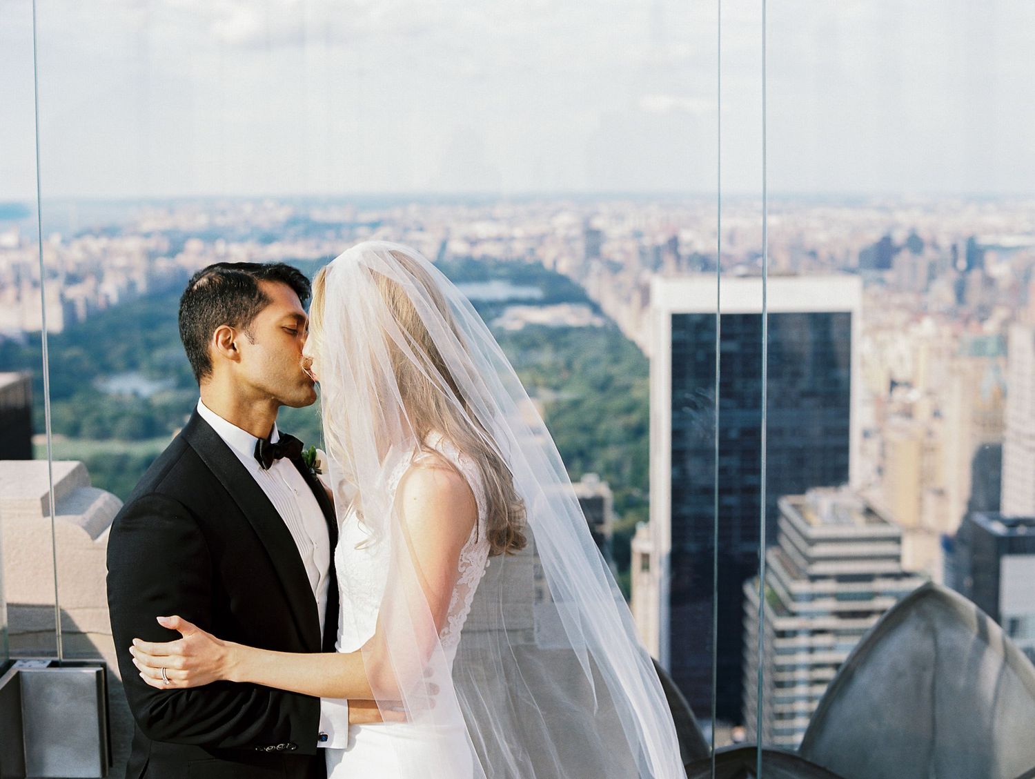 A couple shares an intimate wedding moment overlooking Central Park and Manhattan skyline from a skyscraper rooftop.
