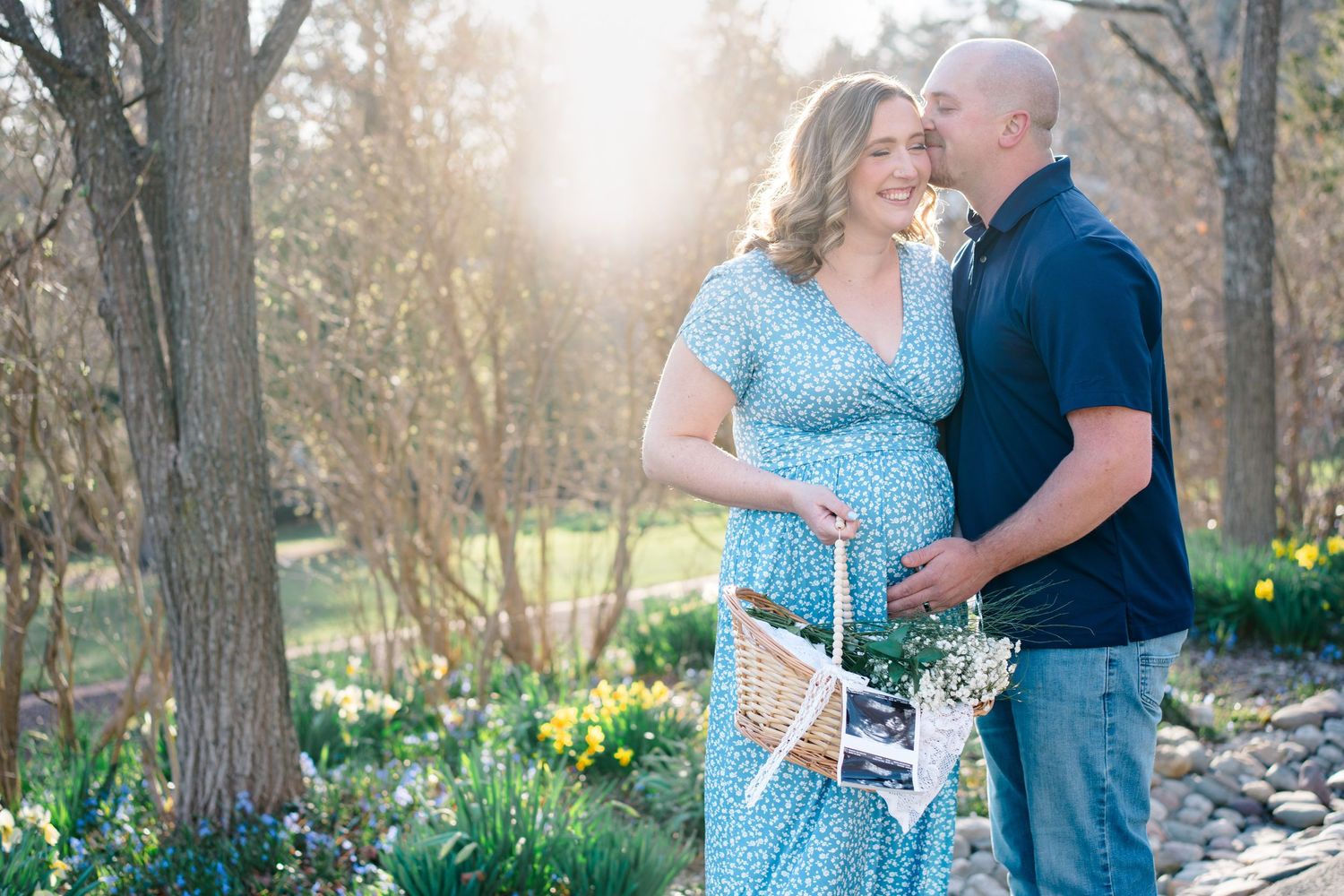 A couple shares an intimate moment in a spring garden filled with blooming daffodils during golden hour sunset.