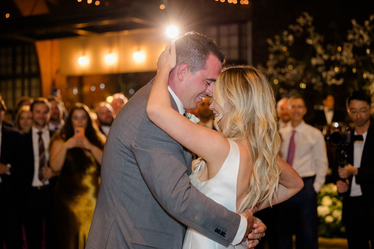 A romantic first dance moment in a warmly lit ballroom.
