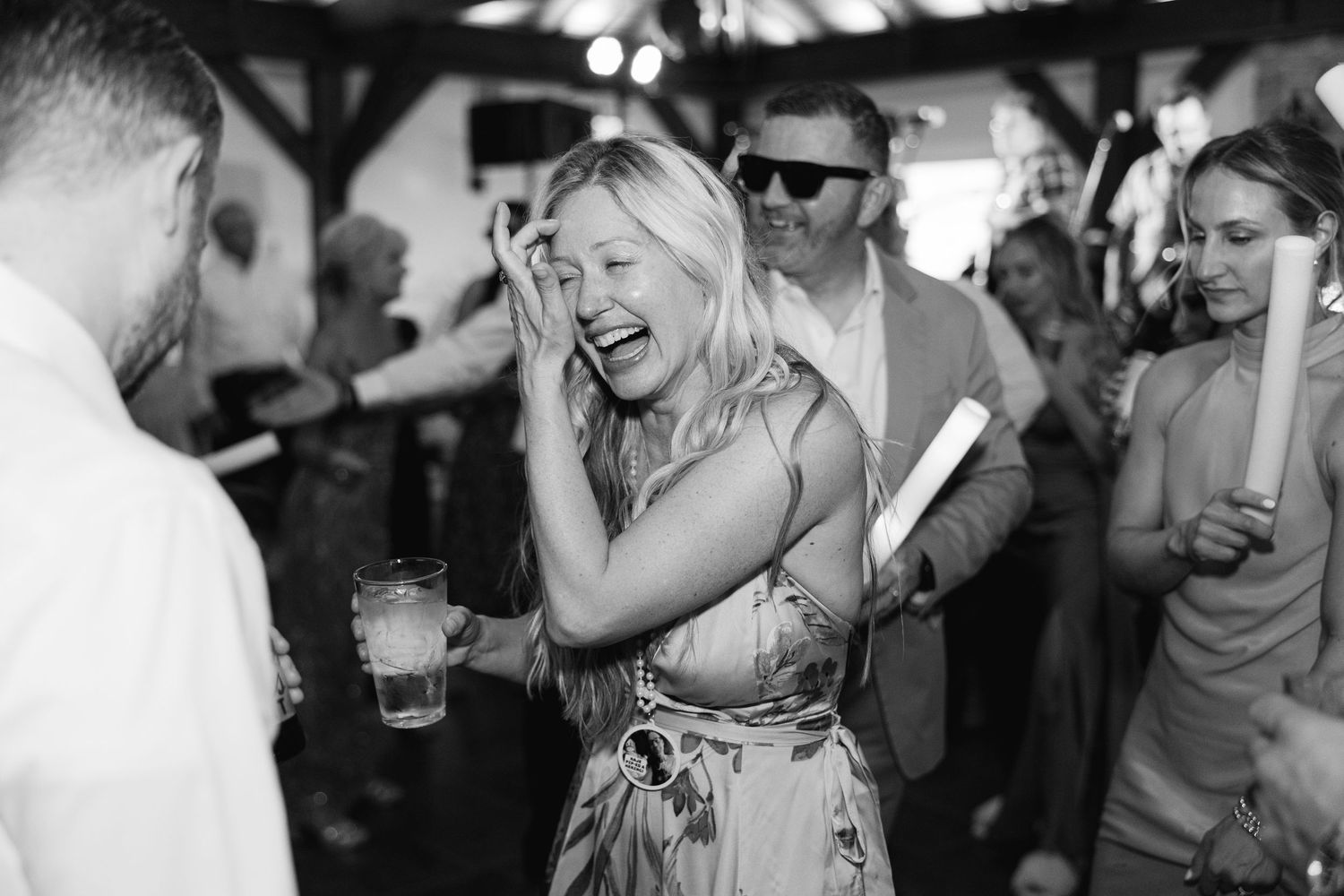 Black and white photo of a joyful wedding guest laughing and dancing at the reception.