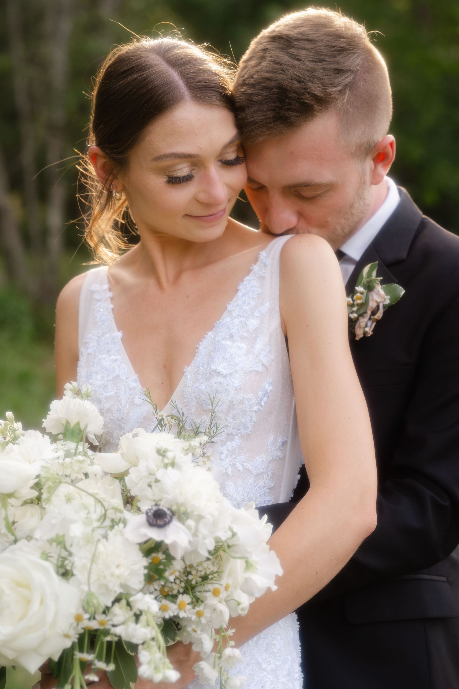 A romantic outdoor wedding moment captured in a series of intimate photos with white flowers.