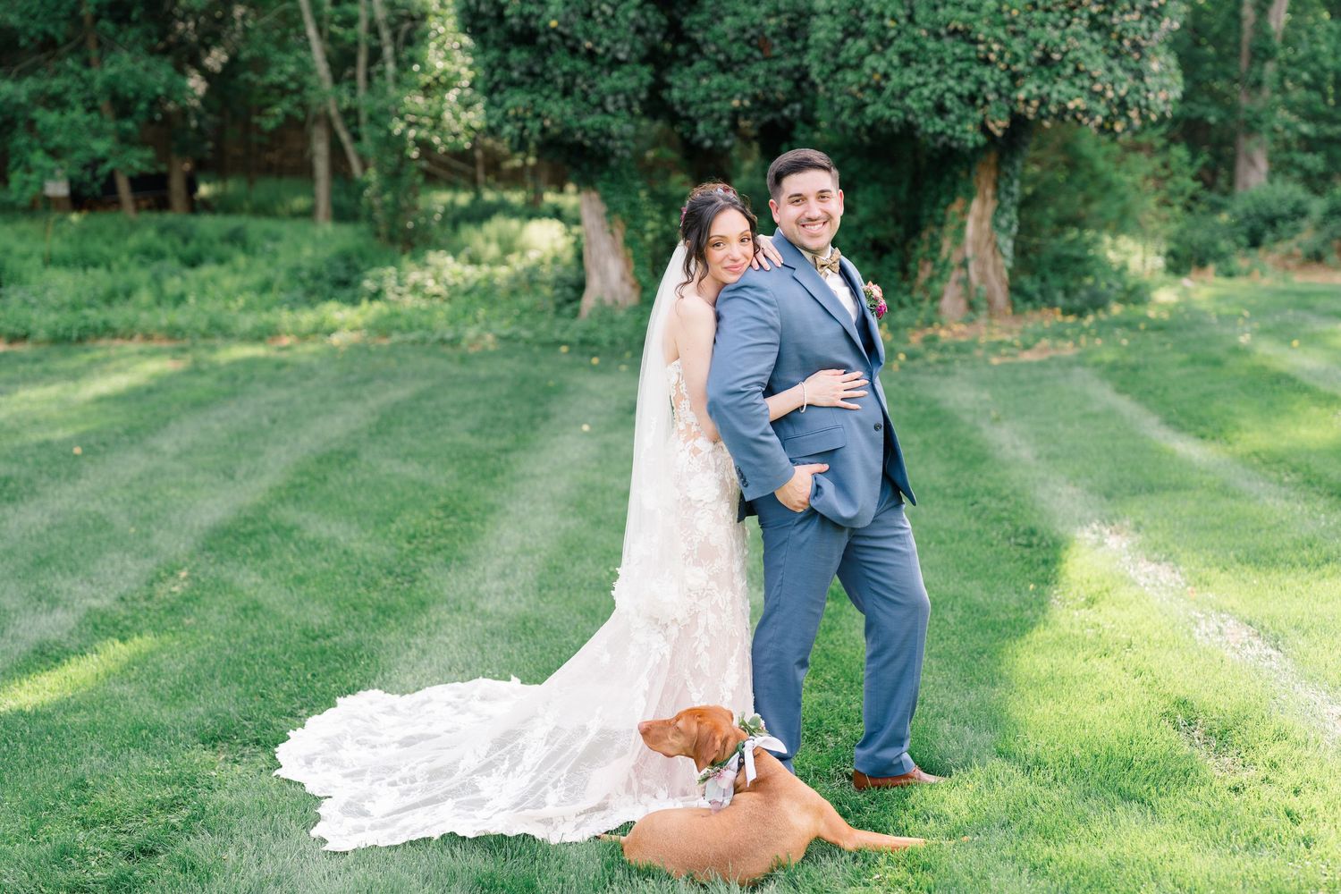 Romantic couple dances in a lush green garden setting with scattered afternoon sunlight filtering through trees.