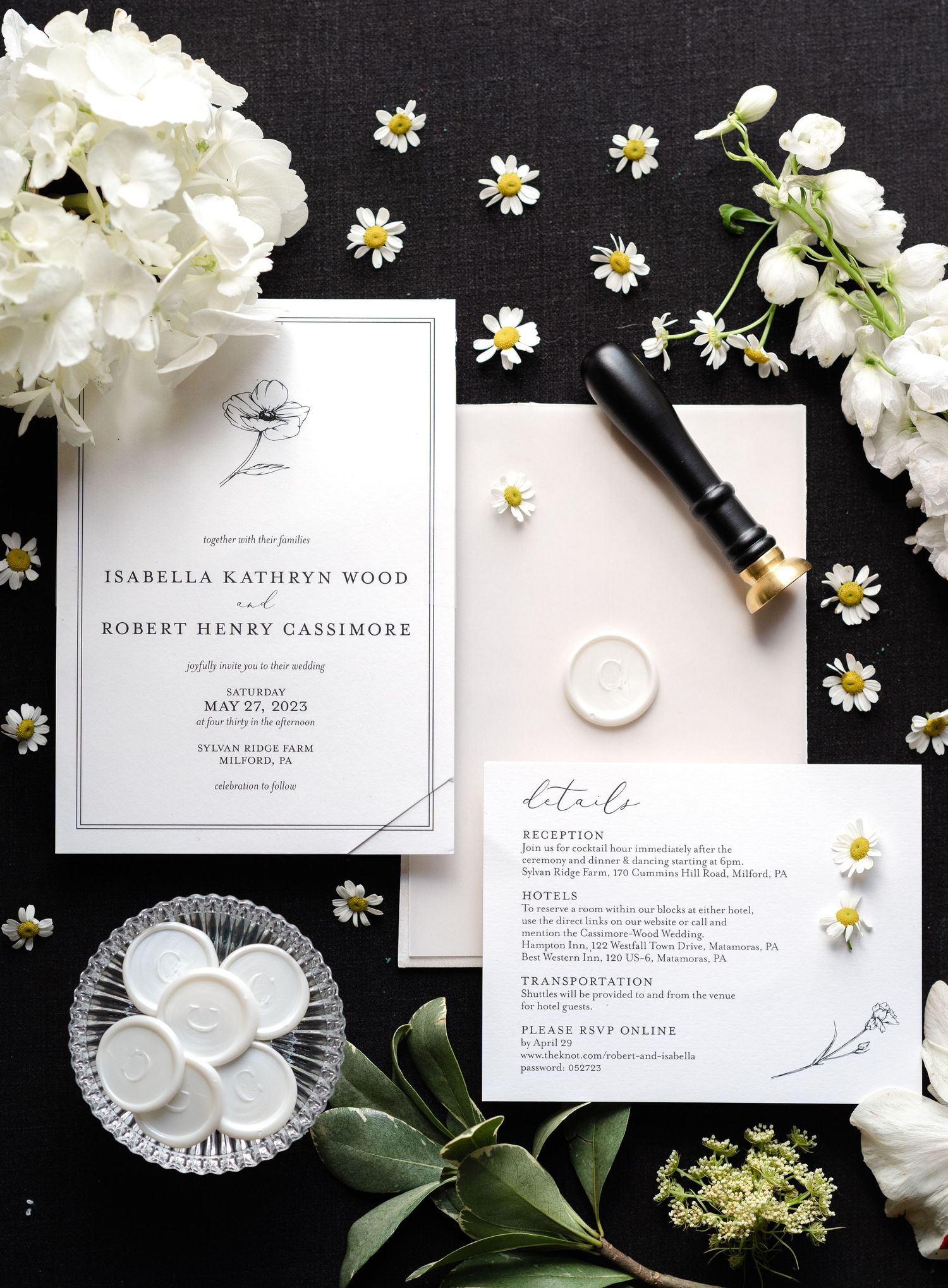 Elegant minimalist wedding invitation suite in white with delicate daisies scattered on black background.