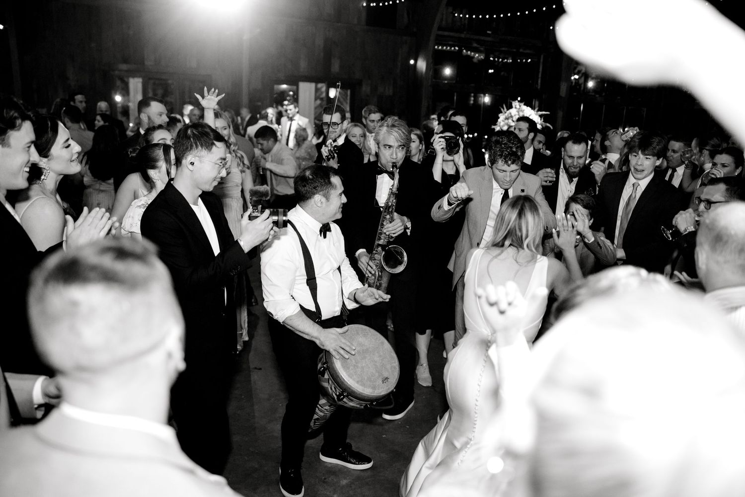 Black and white photo of lively wedding reception dance floor with live band performing.