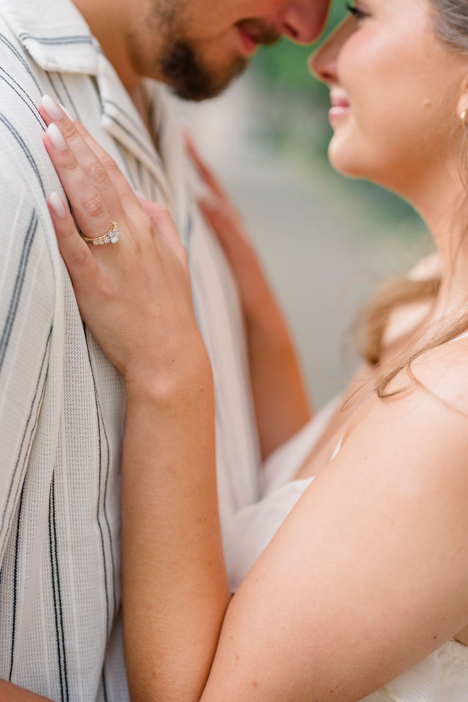 Close-up of a couple nearly kissing, woman's hand on man's chest displaying a diamond engagement ring.