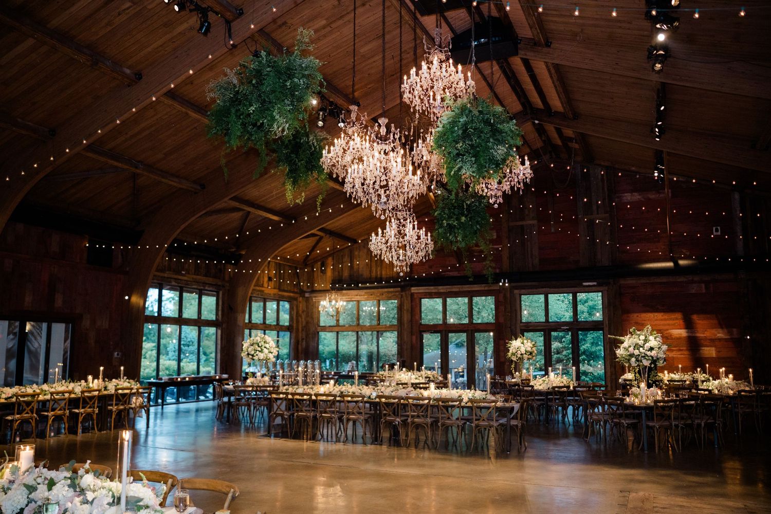 Elegant reception hall with crystal chandeliers and string lights creating warm ambiance.