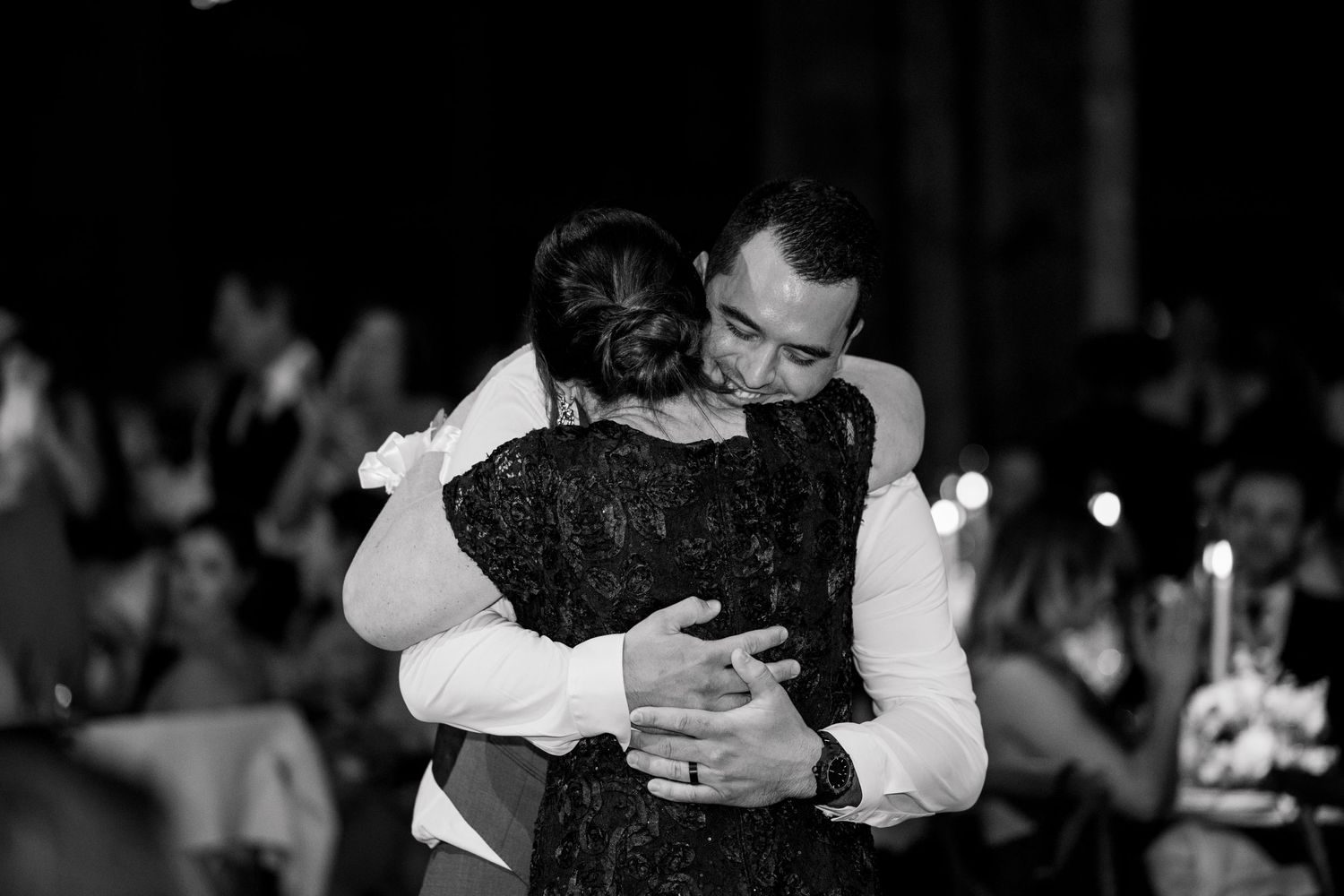 A tender embrace captured in black and white during an emotional dance at a wedding reception.