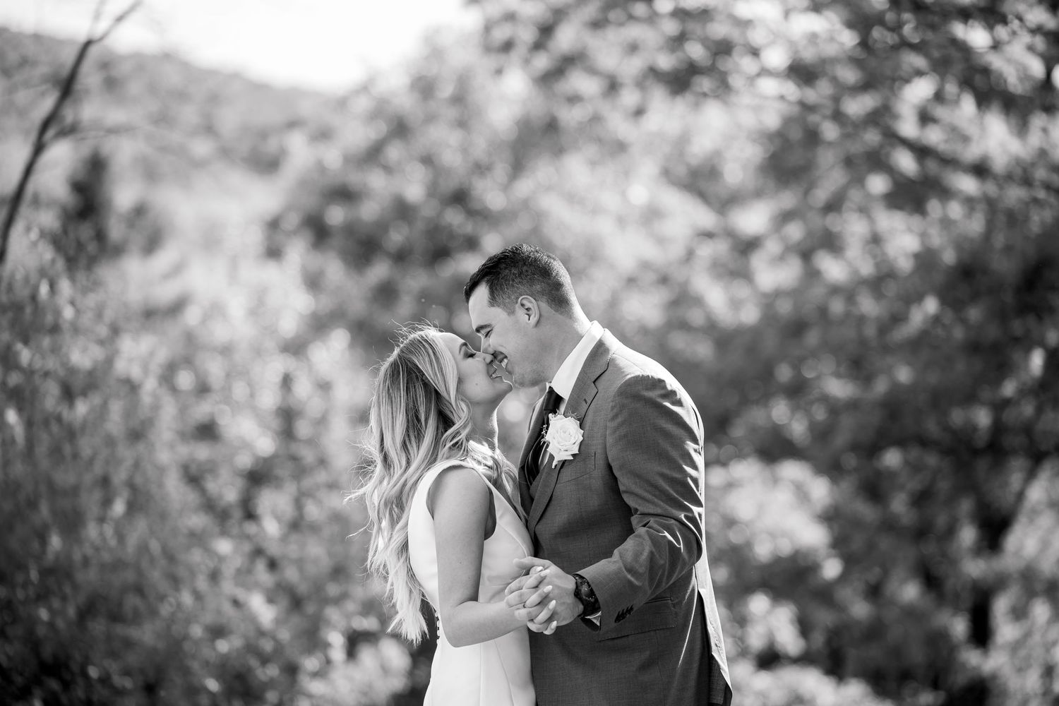 Black and white outdoor portrait of newlyweds sharing an intimate moment in a garden setting.
