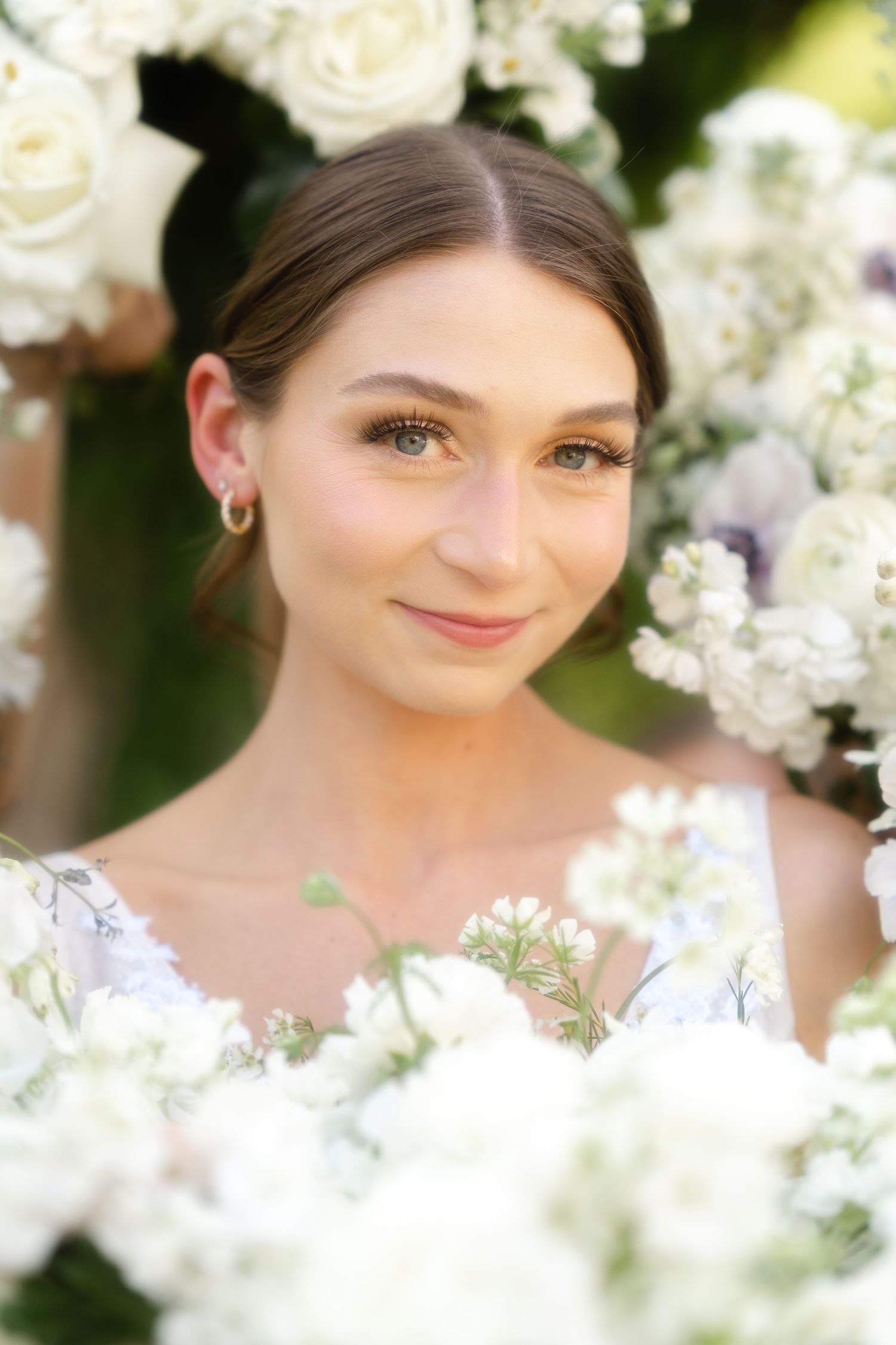 Romantic springtime portrait surrounded by delicate white blossoms and soft natural lighting in garden setting.