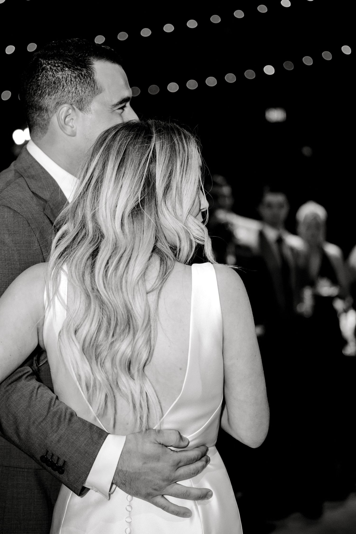 A romantic black and white photo of a couple embracing during their wedding dance.