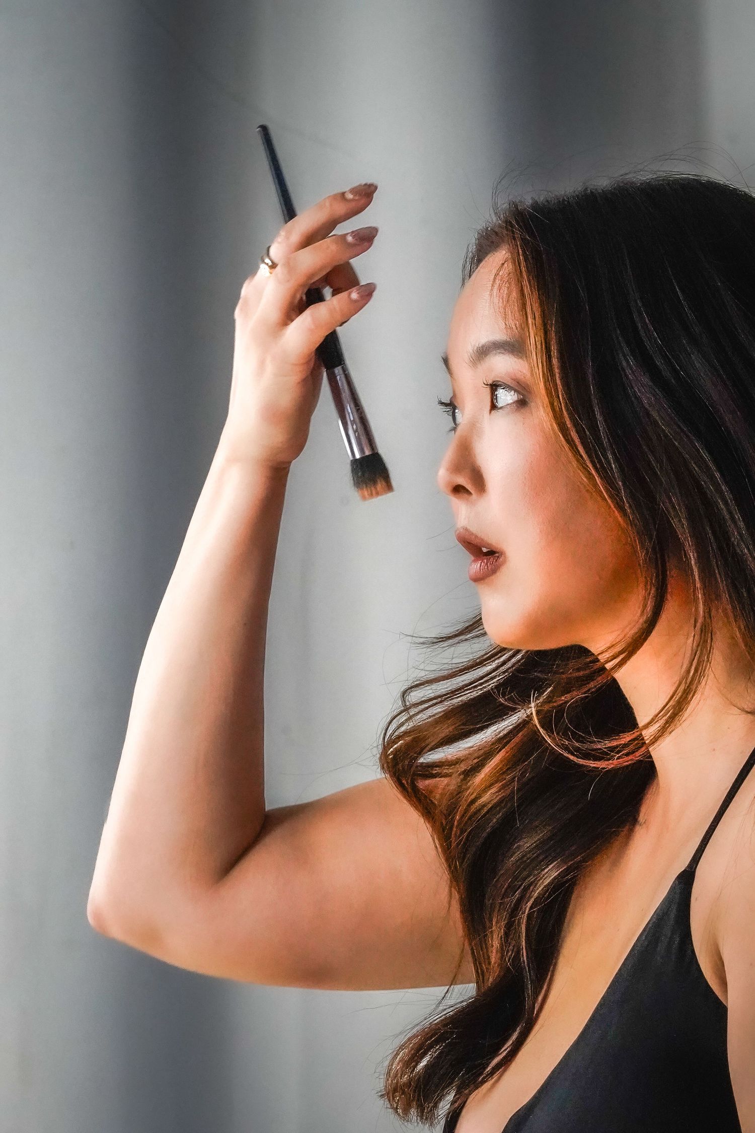 Side profile shots of someone looking up while wearing dark clothing against a gray background.