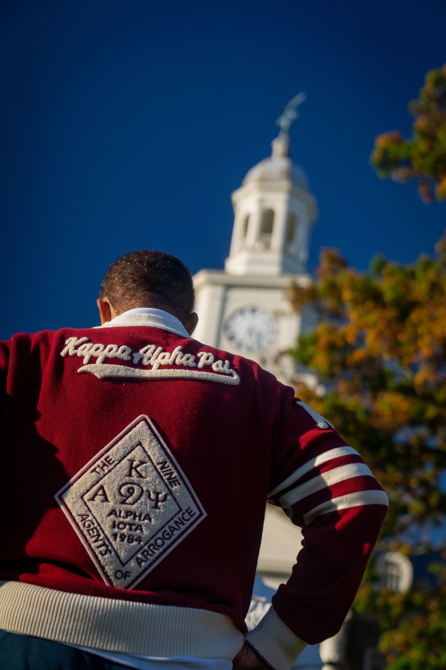 Red and white Kappa Alpha Psi fraternity letters against a blue sky with a church steeple in the background.
