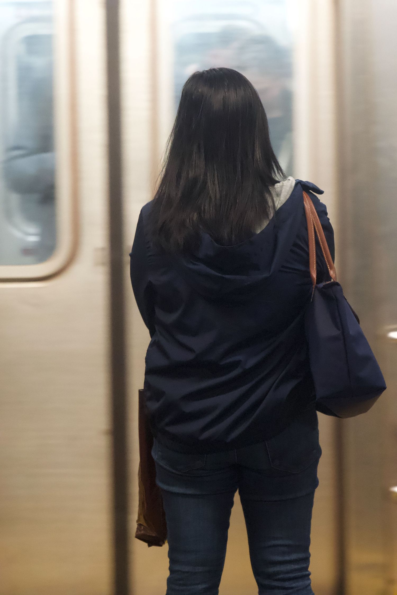 Passenger standing in subway car looking out window during commute.