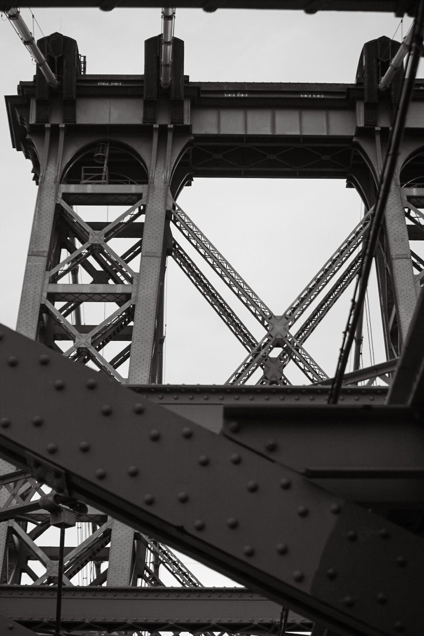 Black and white architectural detail of steel bridge support beams and rivets.