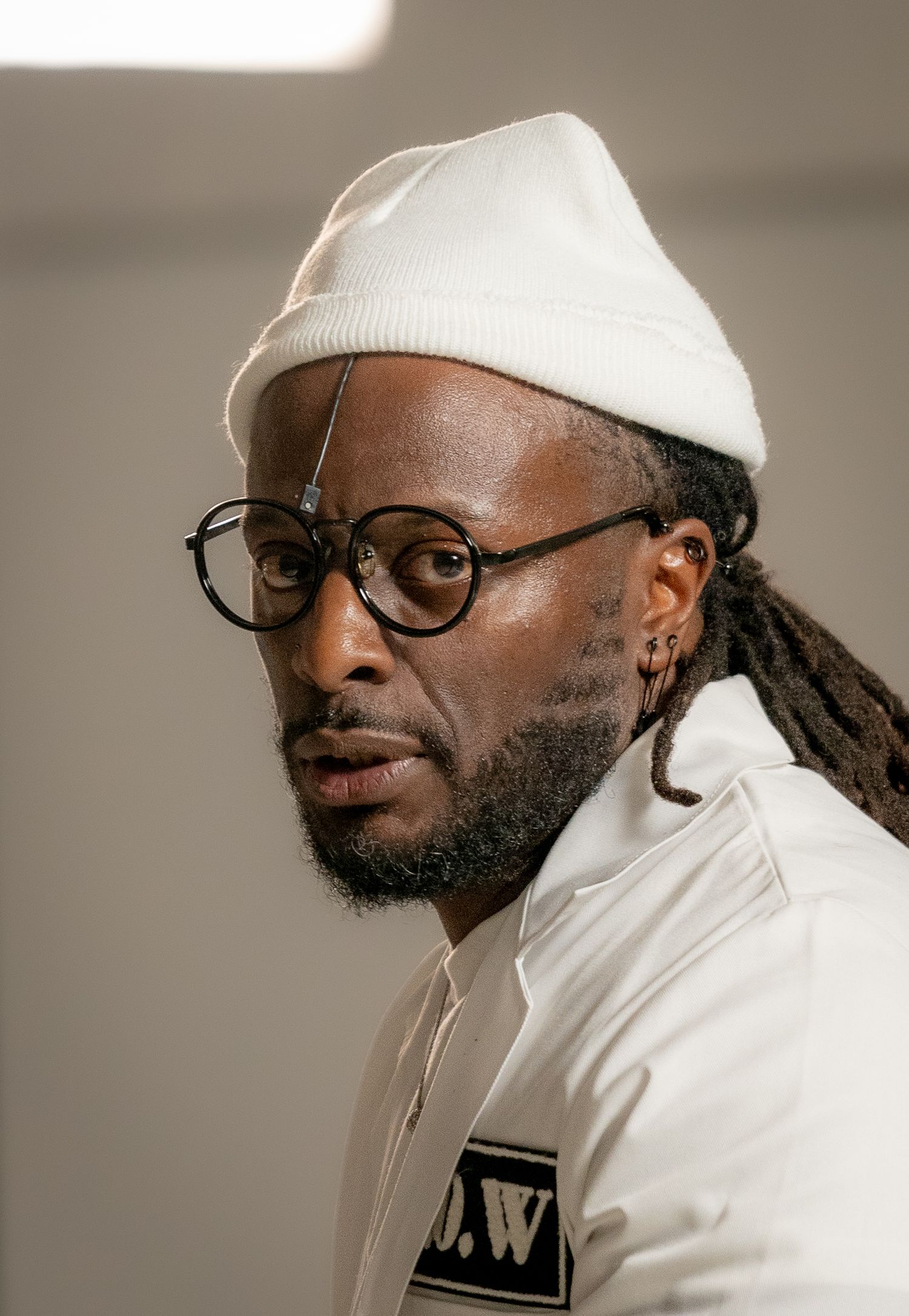 Portrait series showing person in white beanie and glasses against neutral background.