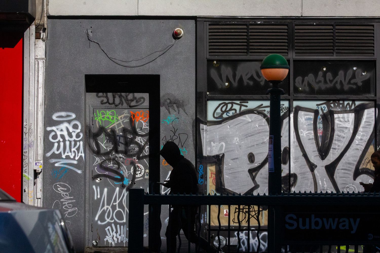 Graffiti covered subway entrance with black walls and red accent.