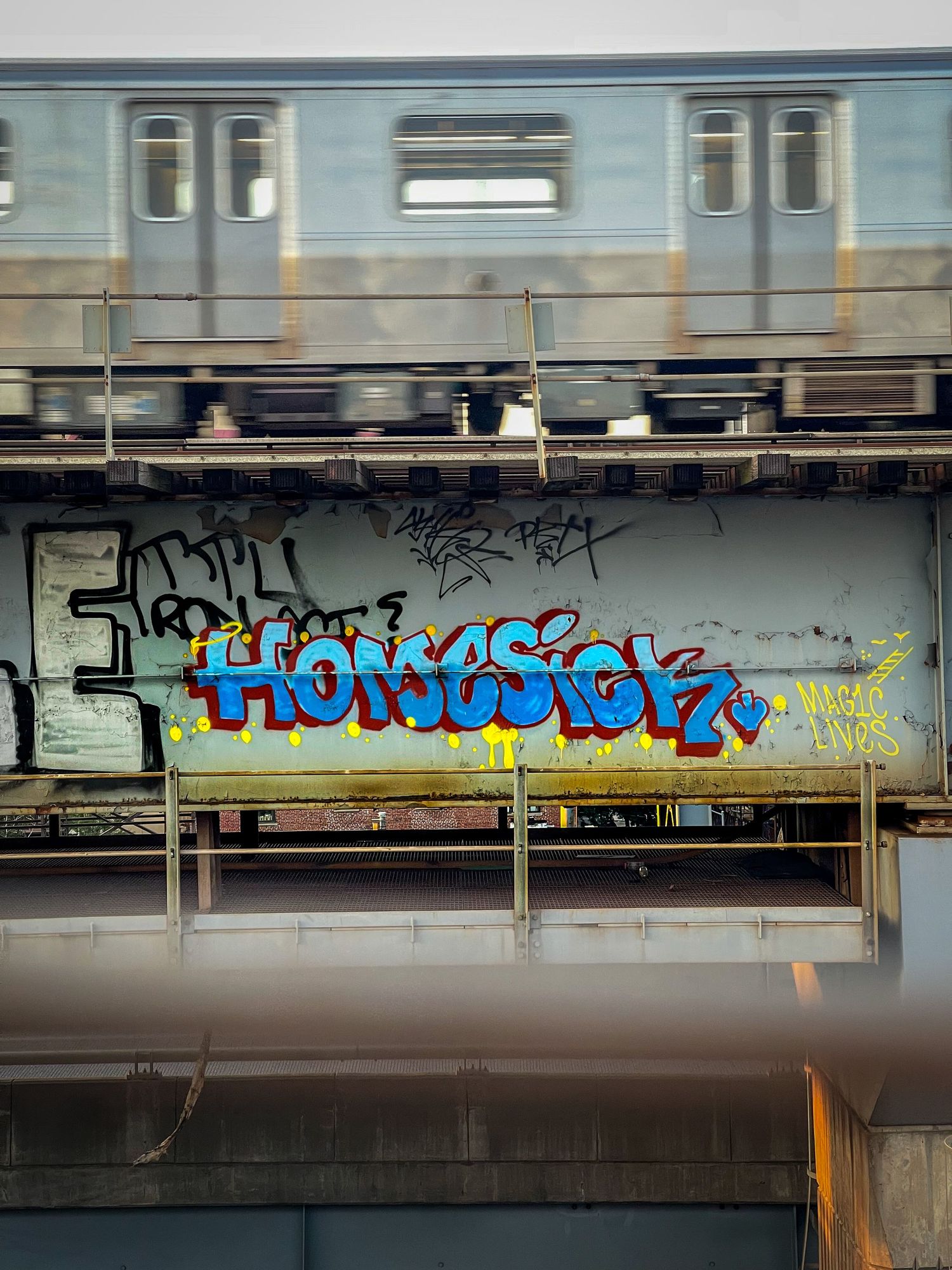 Moving subway train with colorful graffiti art painted underneath.