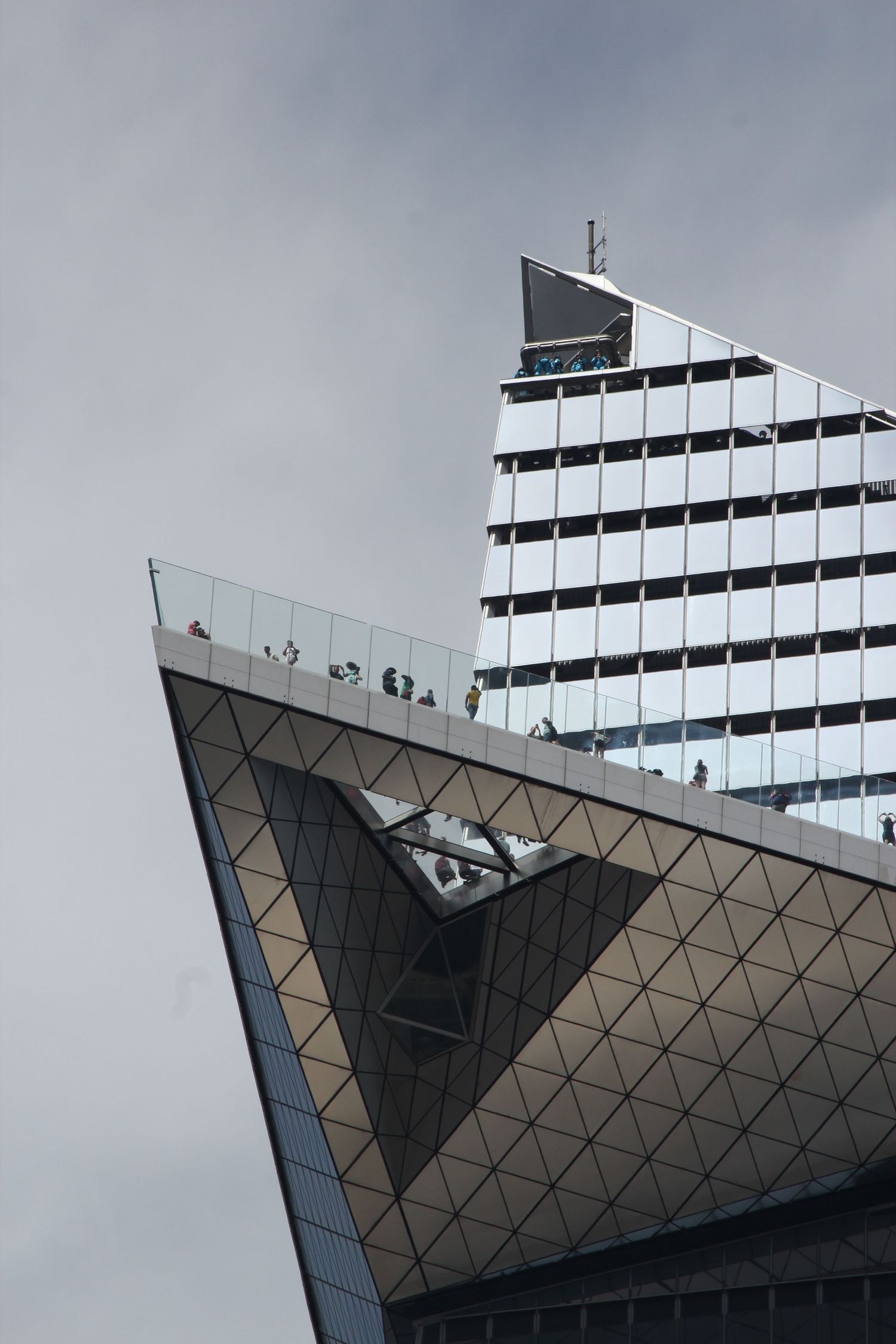 Modern geometric architecture of glass building against cloudy sky.
