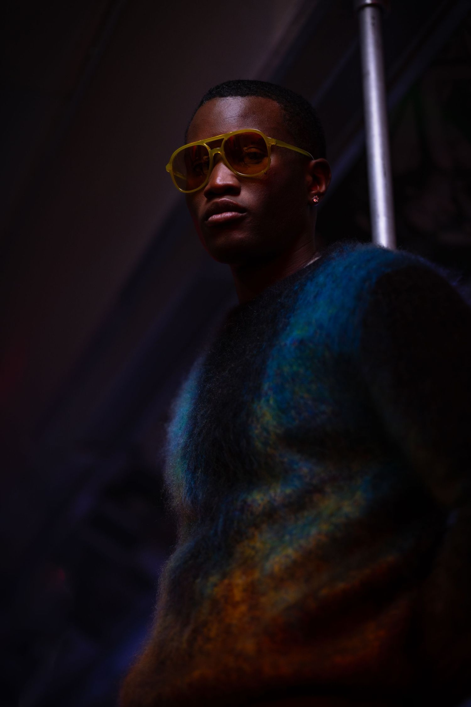 Artistic portrait with dramatic lighting showing sunglasses and blue-tinted shadows.