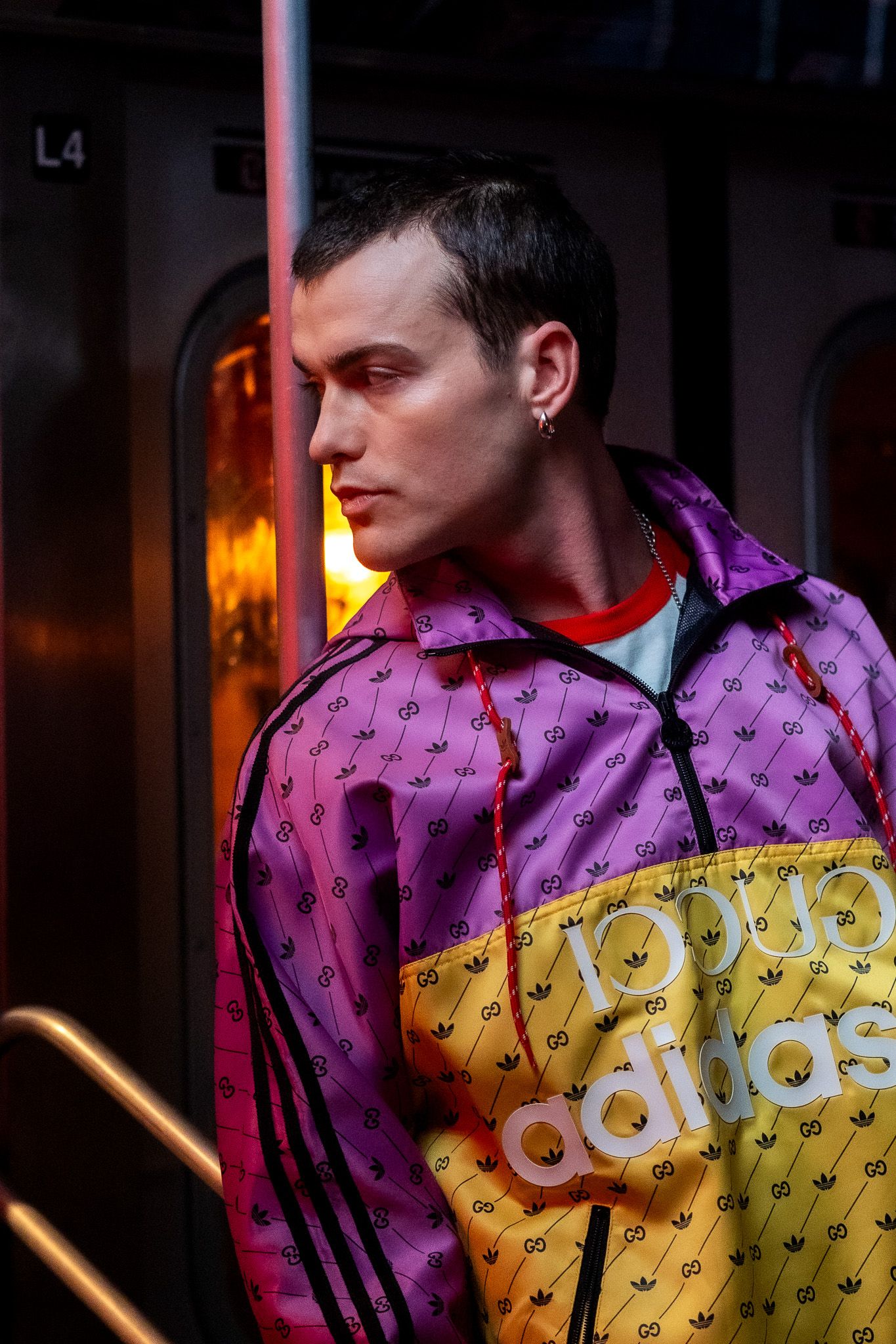 Person wearing a vibrant purple and yellow color-blocked jacket in a dimly lit setting.