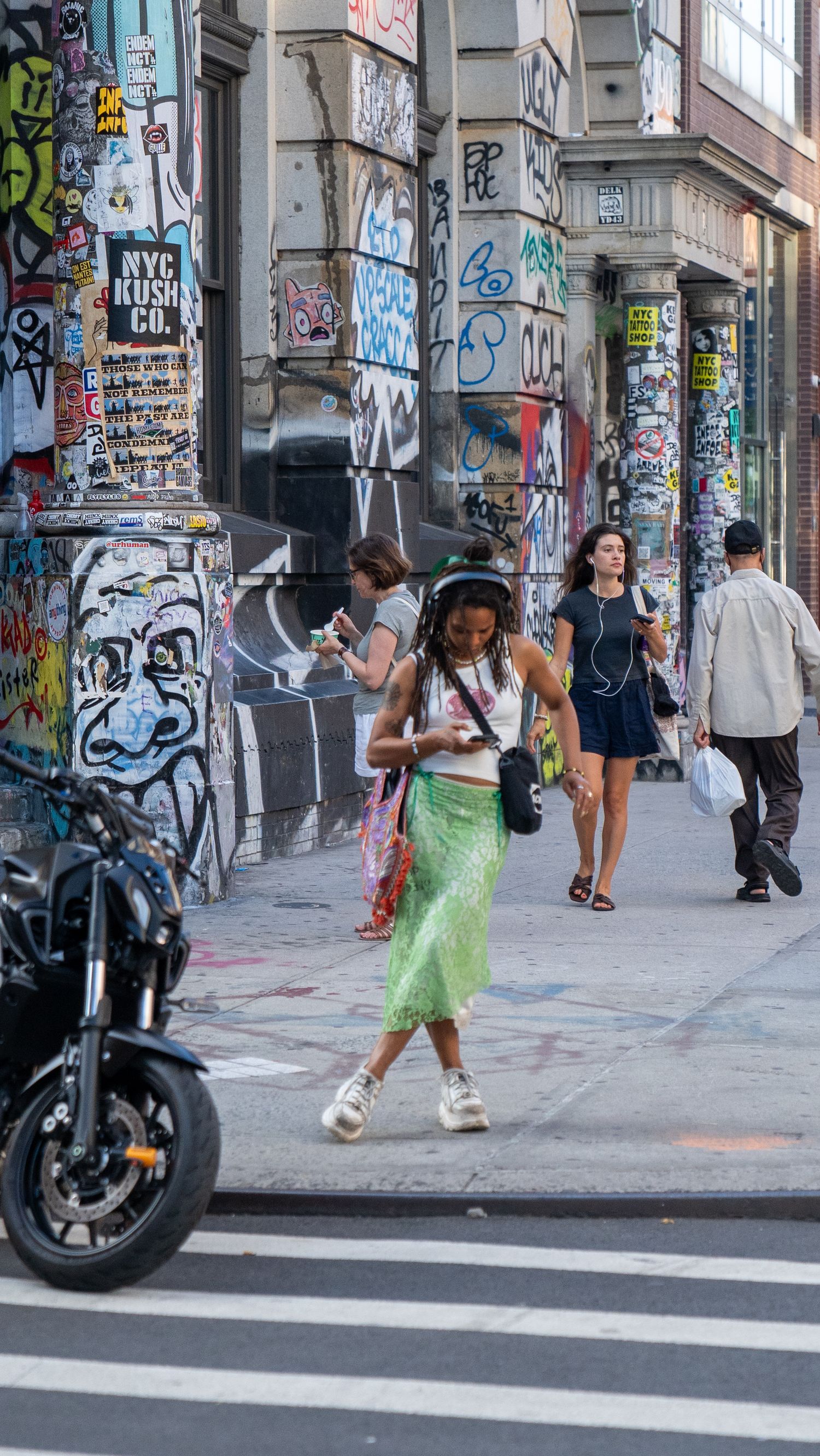 A person in a green dress dances on a graffiti-covered street corner.
