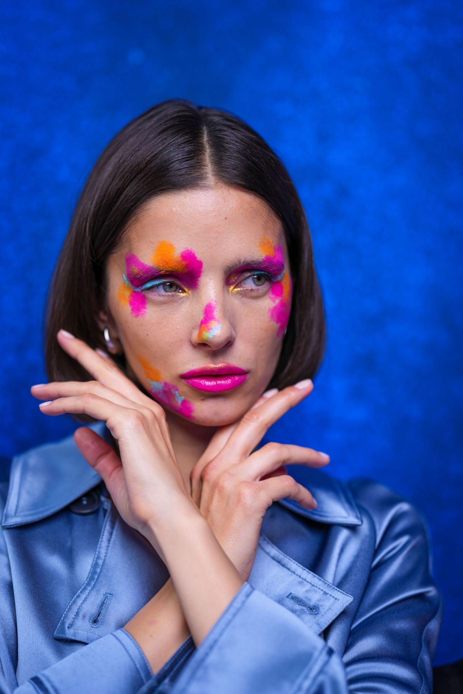 Creative beauty shot with bright pink makeup and star details against vibrant blue background.