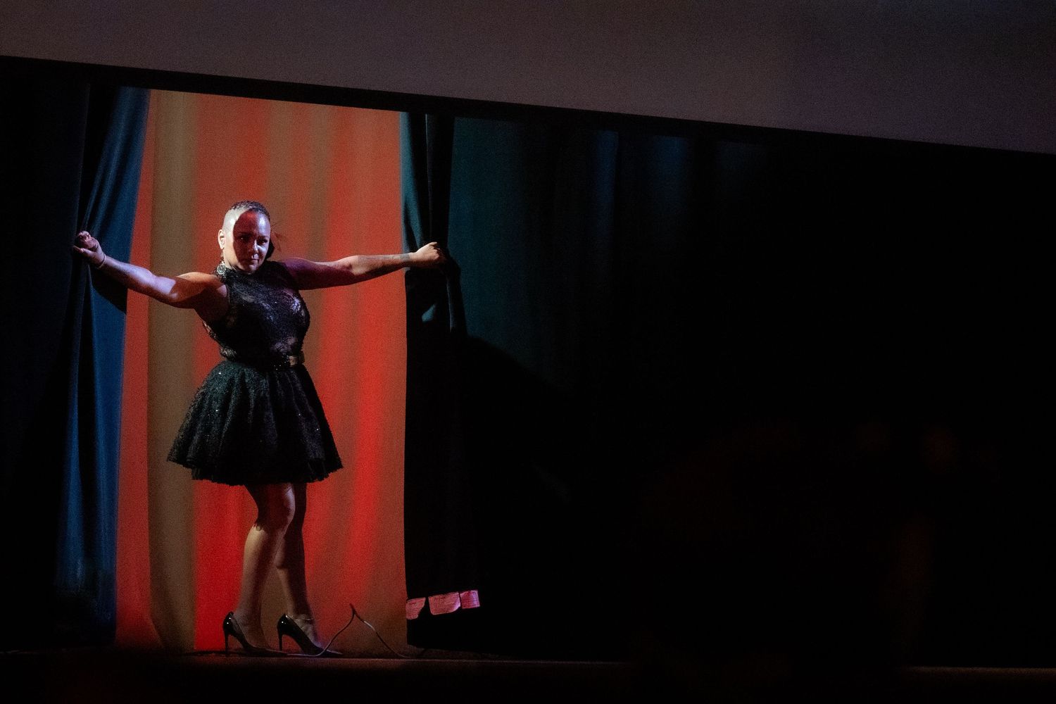 Silhouettes of dancers performing on a dark stage with dramatic lighting.