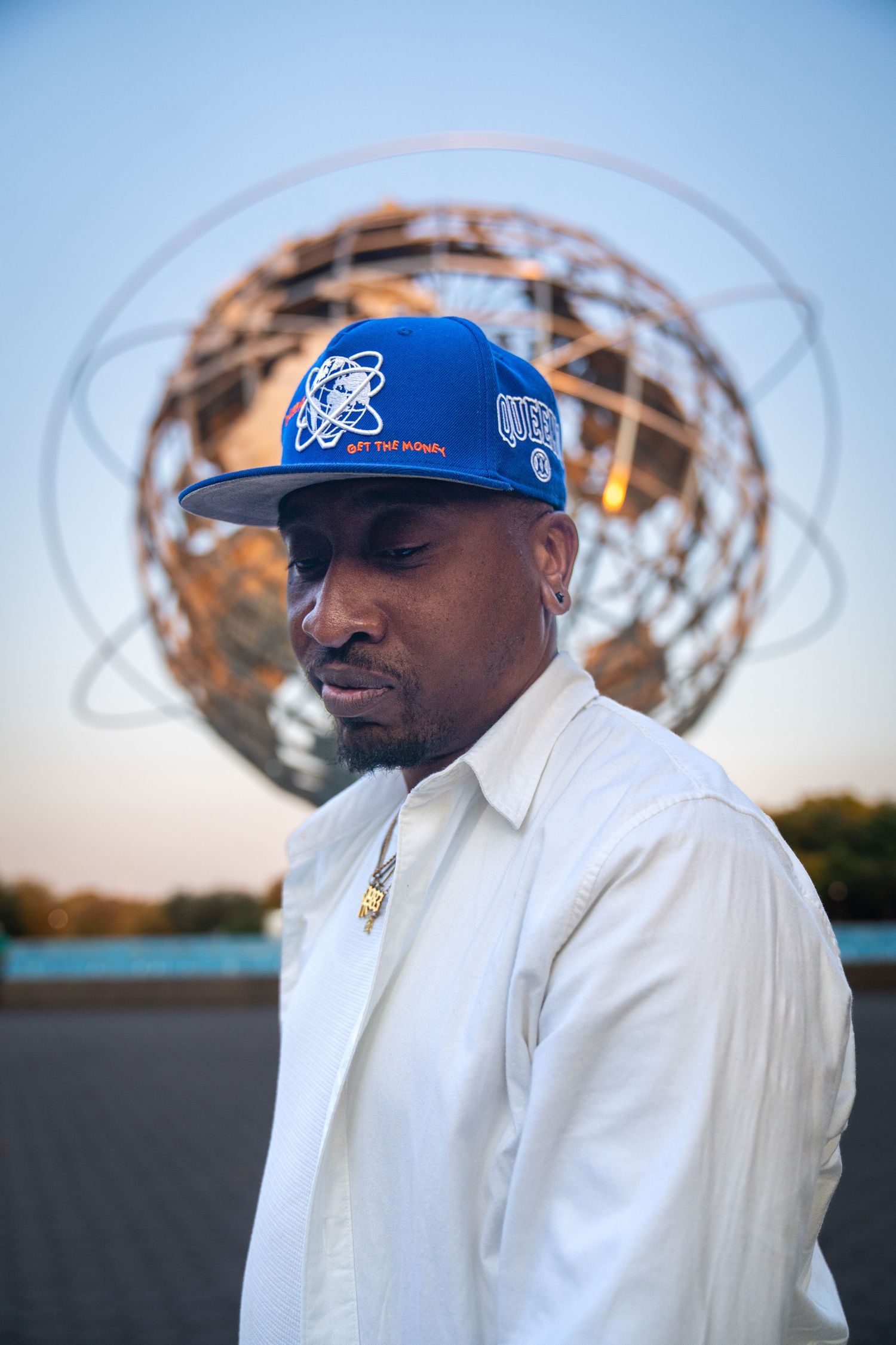 Person in white clothing and blue cap photographed against blurred outdoor structures.