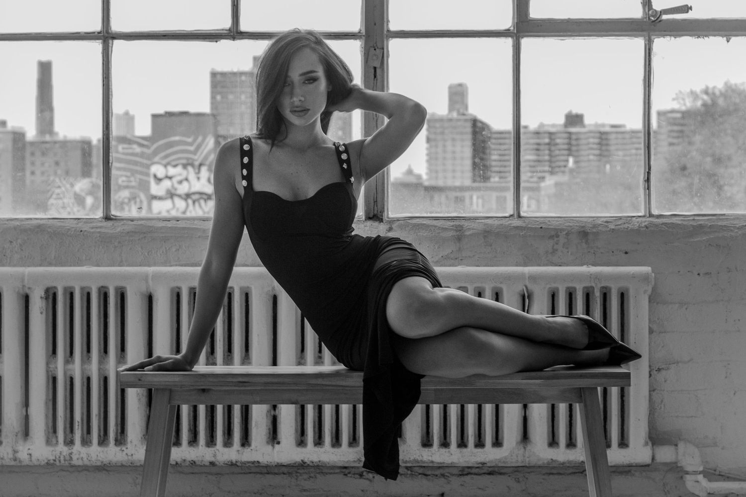 Silhouette of a dancer stretching gracefully near large industrial windows.