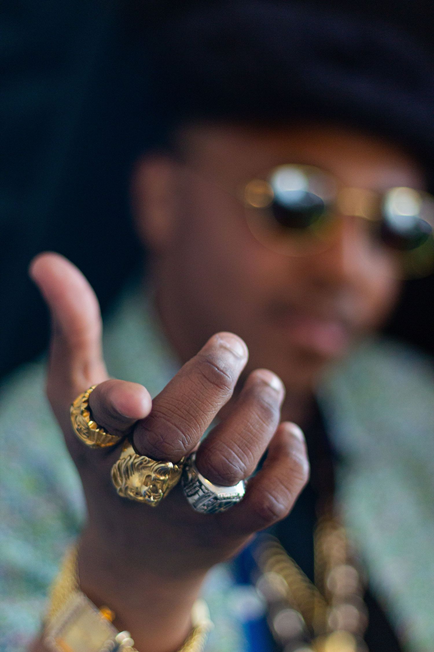 Detail shots of hands showing multiple gold and silver rings in dramatic lighting.