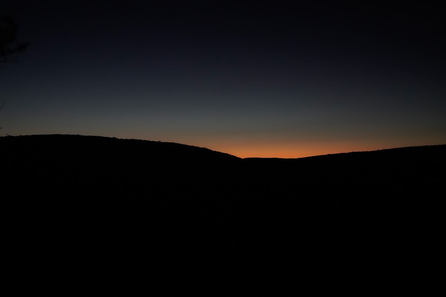 Minimalist landscape silhouette at sunset showing rolling hills against an orange sky.