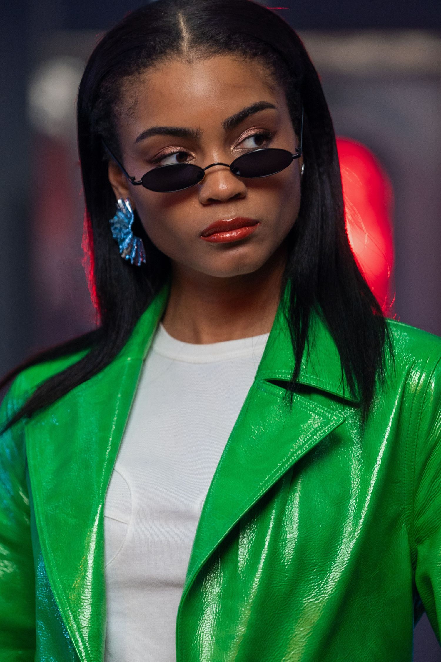 Fashion portrait featuring bright green patent leather jacket and stylish sunglasses.
