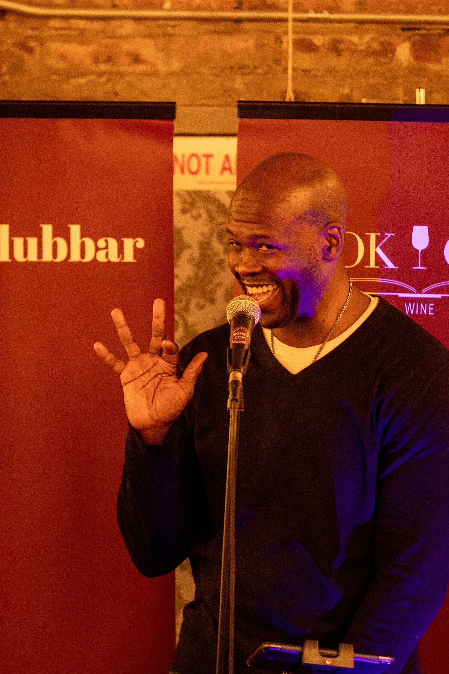 Performer on stage at Book Club Bar with dramatic red lighting.