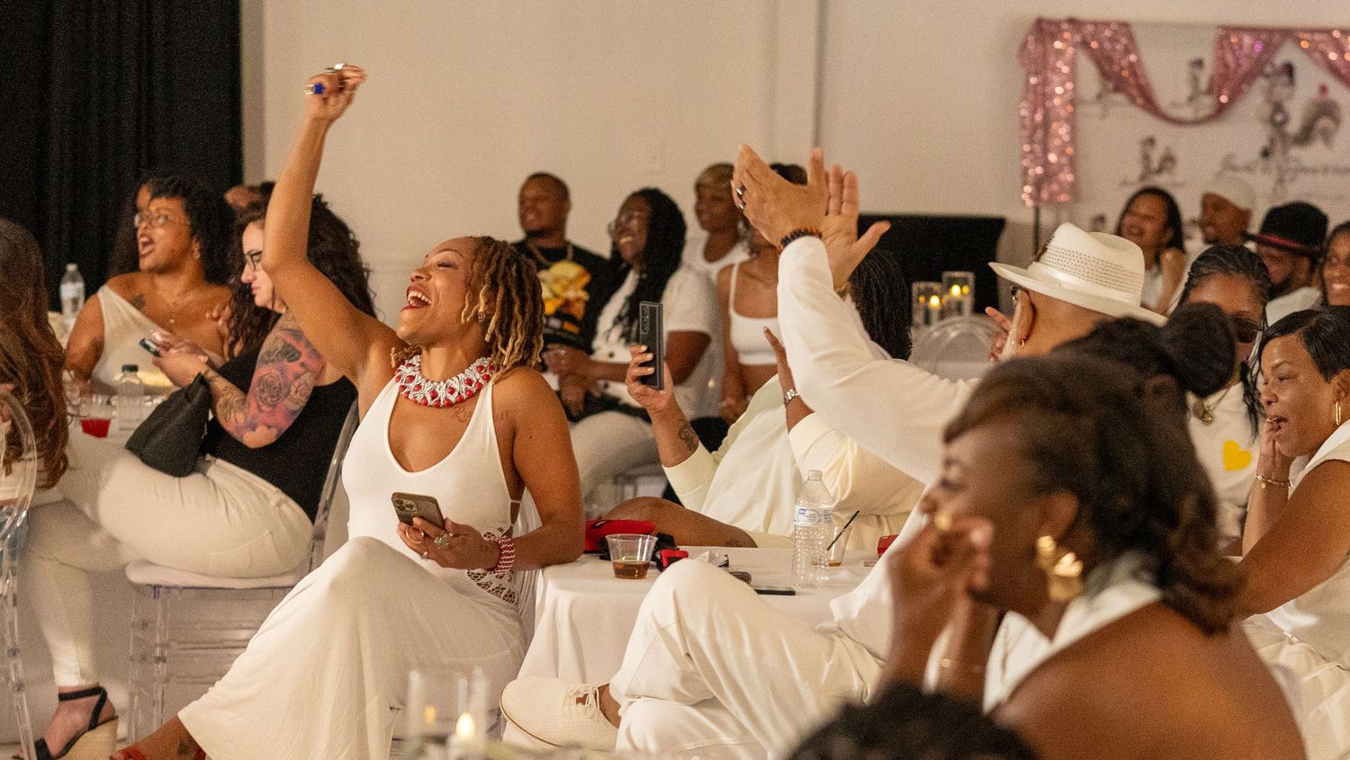 Crowd of people in white attire celebrating at an indoor event.