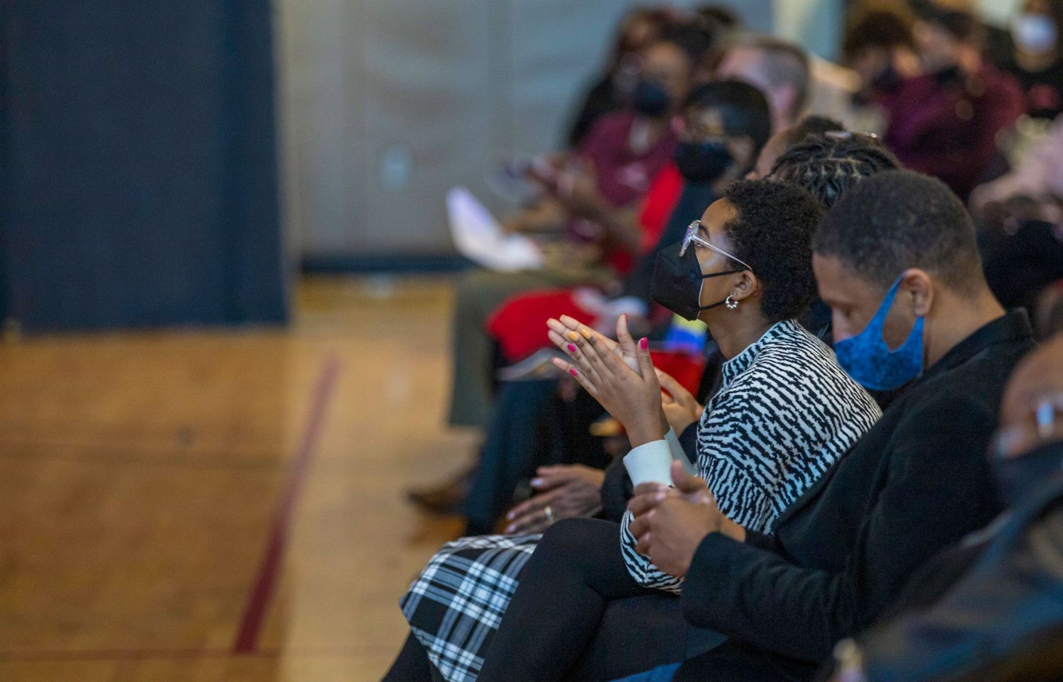 Audience members wearing masks applaud during an indoor performance.